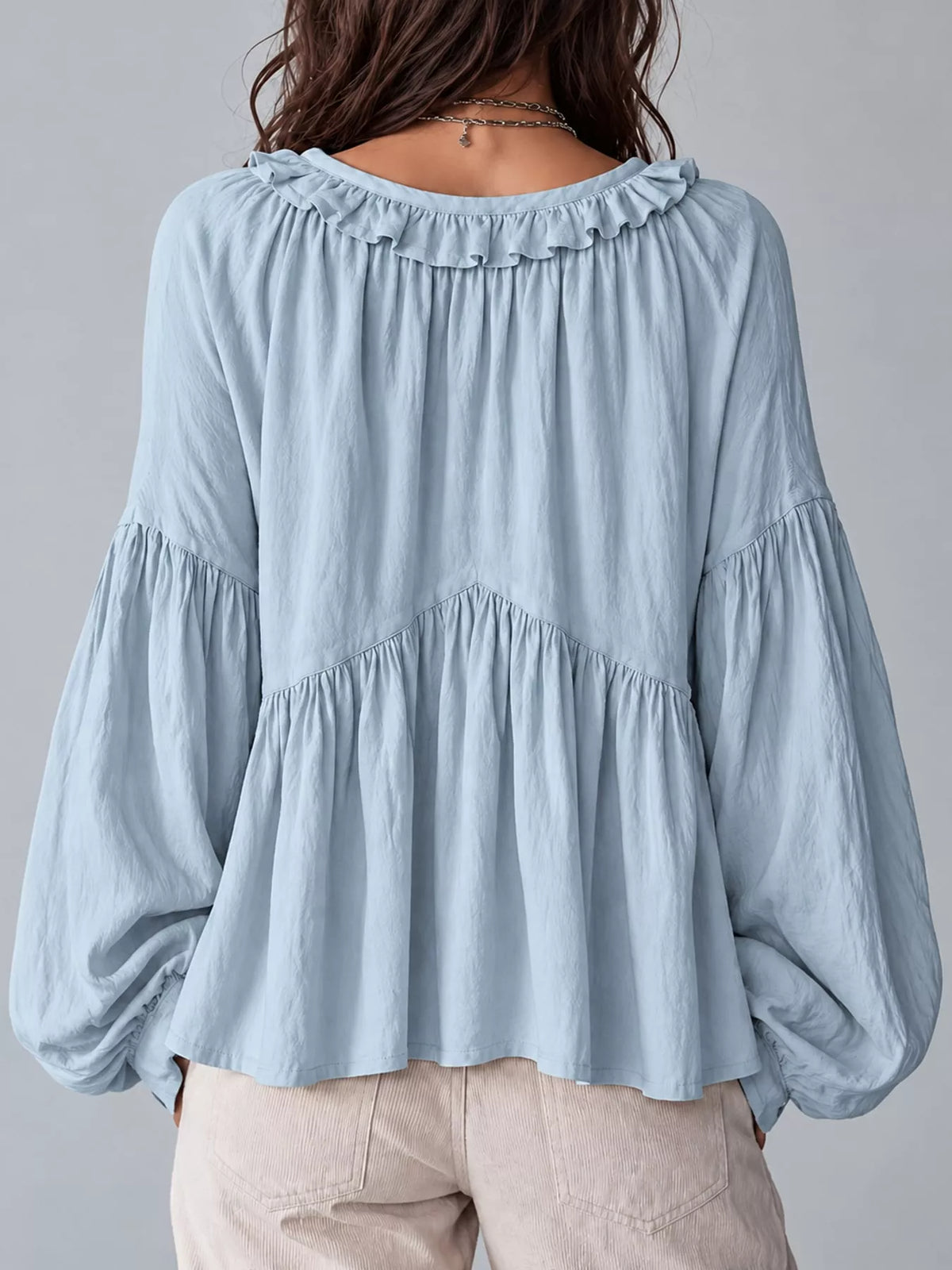 Light blue ruffled v neck blouse, back view