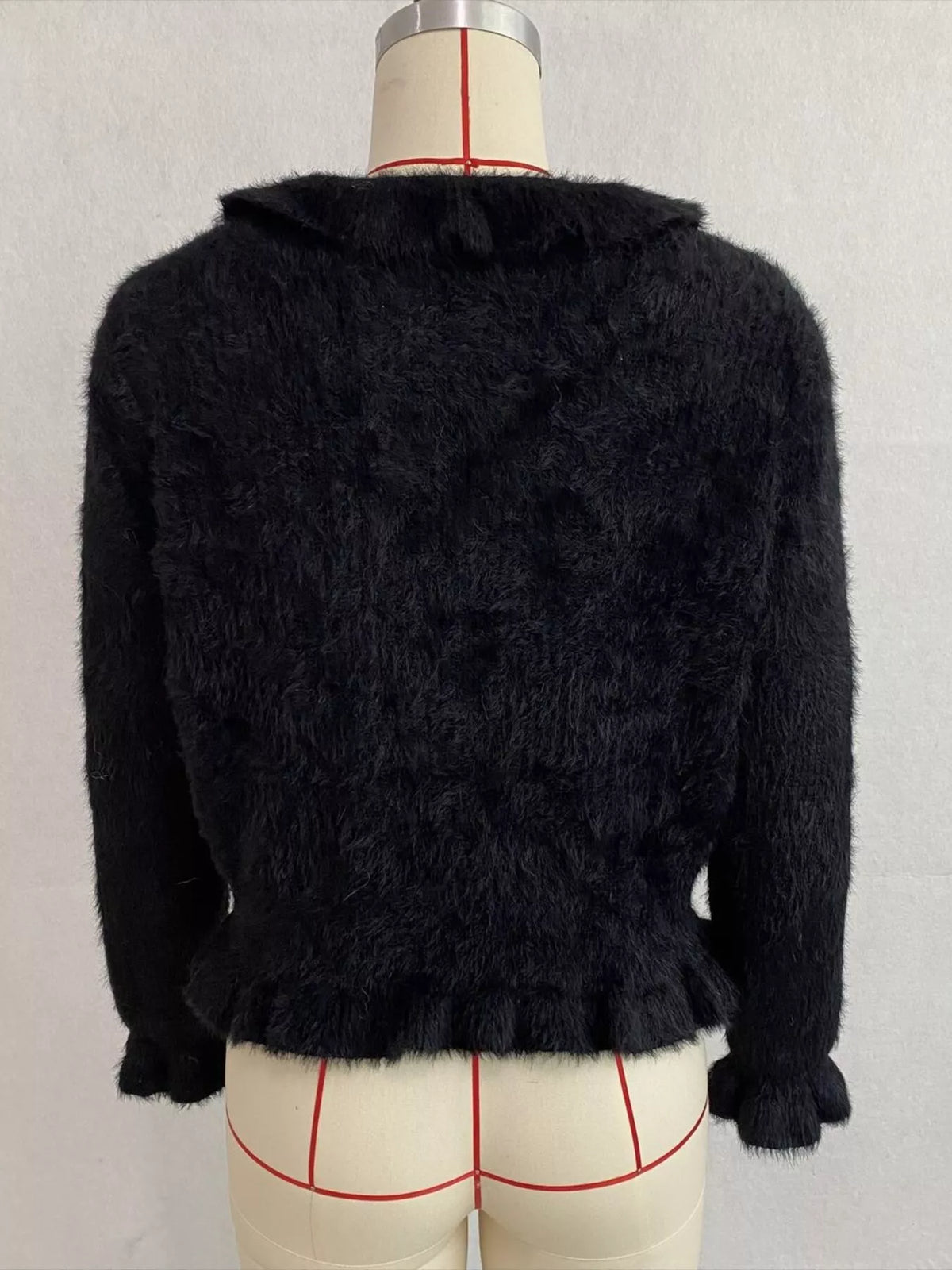 Black fuzzy ruffle-trim button-front cardigan, back on dress form.