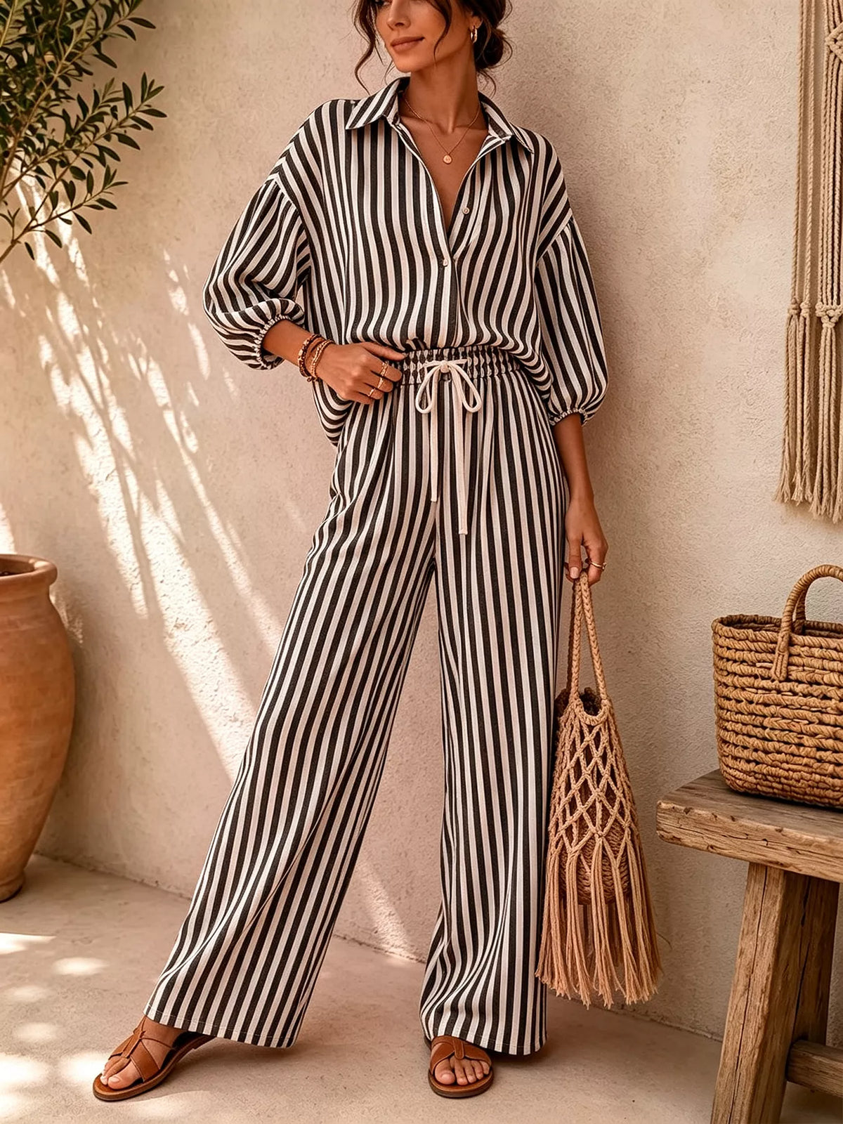 Black and white striped shirt and drawstring pants set, front view with hand at waist