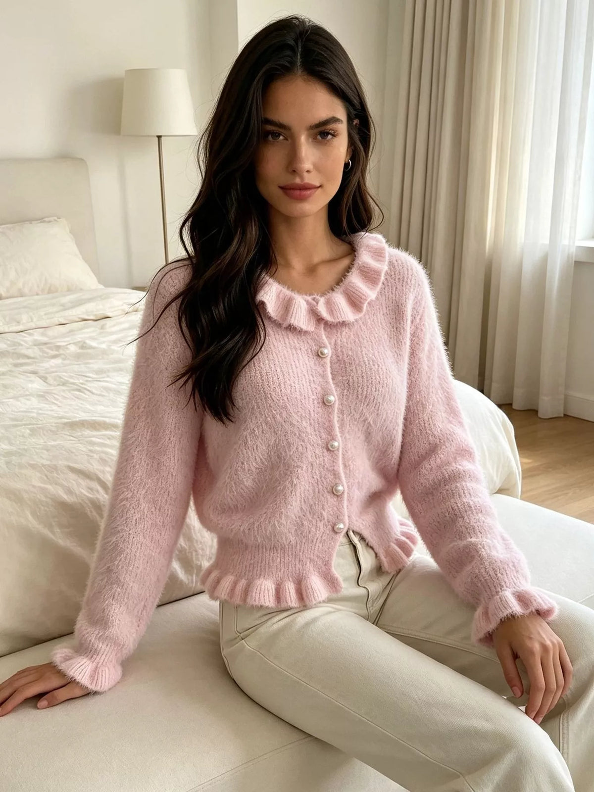 Pink fuzzy ruffle-trim button-front cardigan, seated front view.