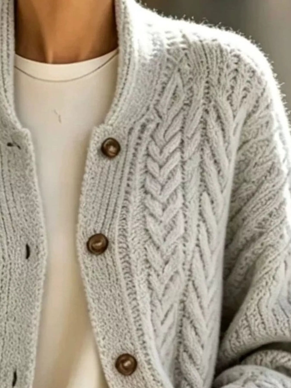 Light gray longline cable-knit button-front cardigan, cable knit and button detail.