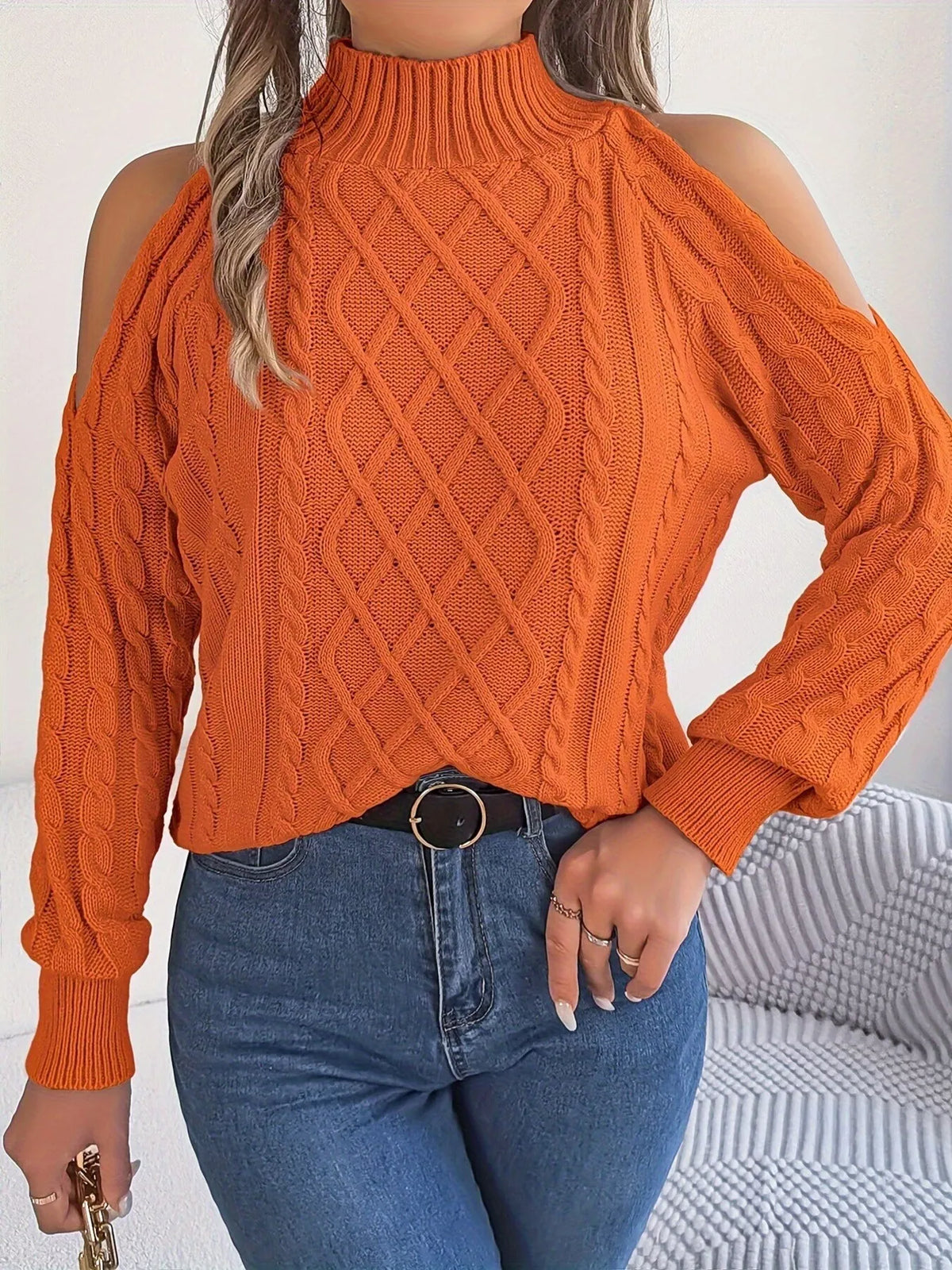 Orange cold-shoulder cable-knit sweater, front with hand at waist.