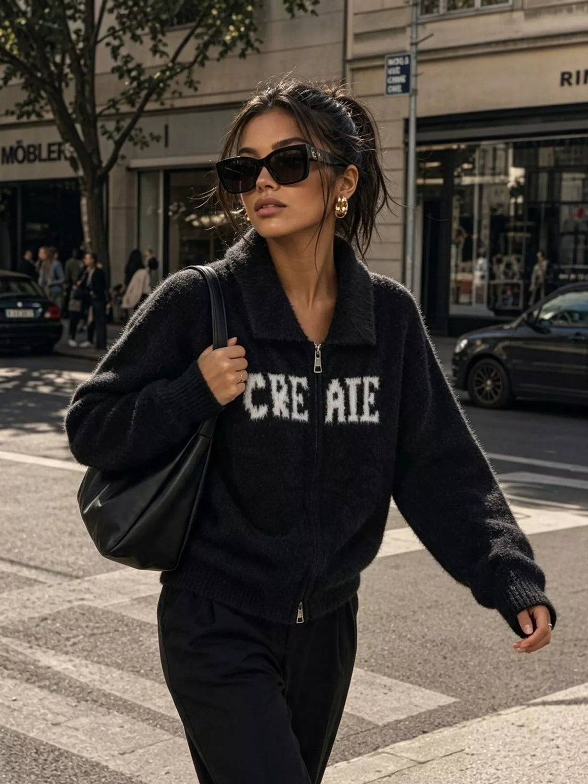 Black fuzzy letter zip-up cardigan, walking front view.