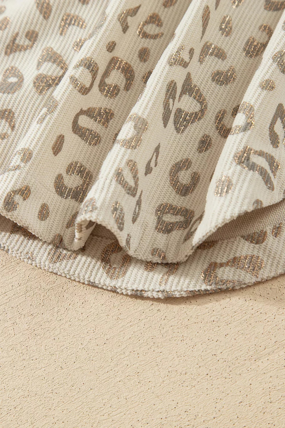 Beige leopard corduroy button-front jacket, curved hem detail.