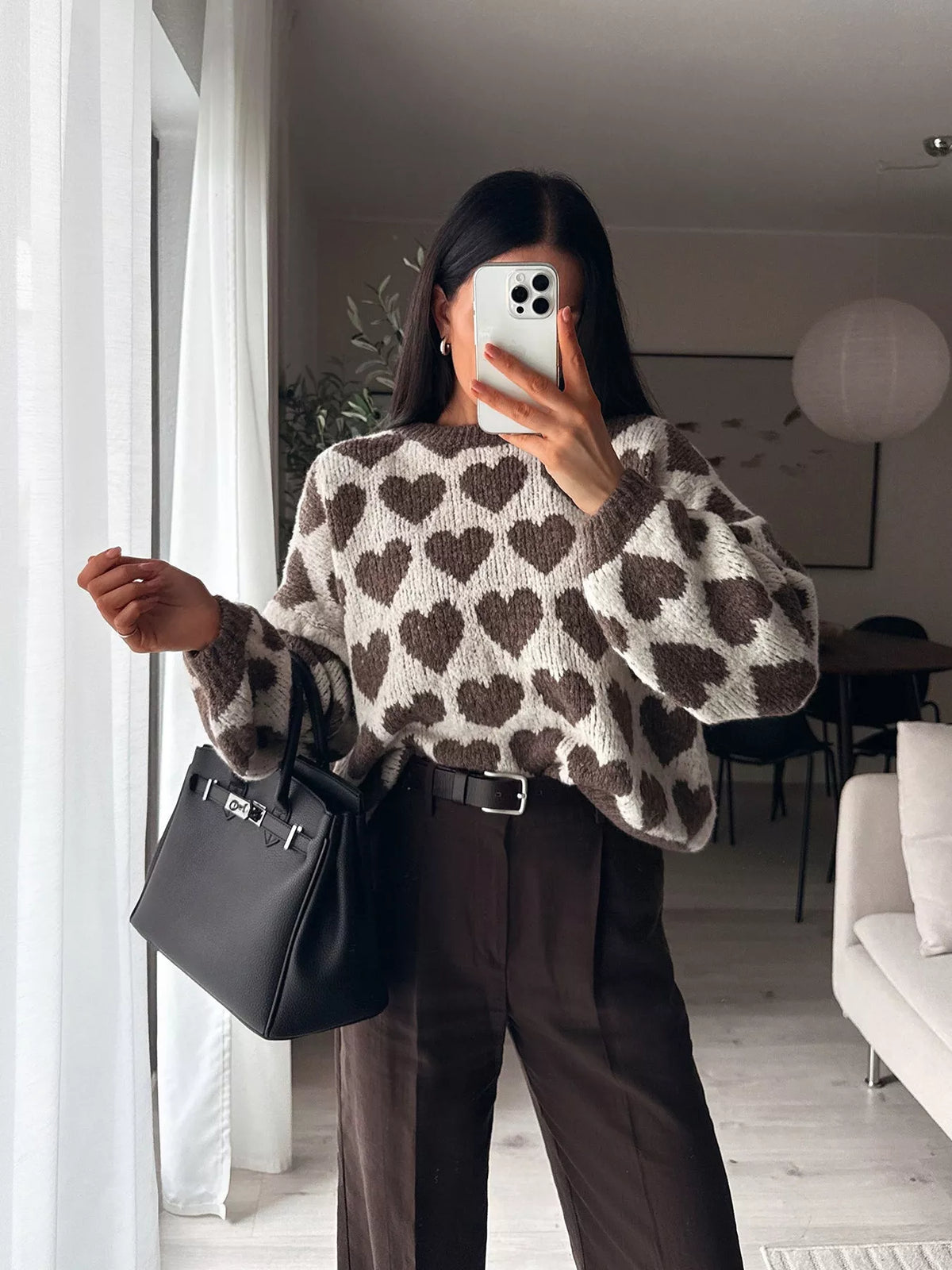 Cream and brown allover heart dropped-shoulder sweater, front with extended hand.