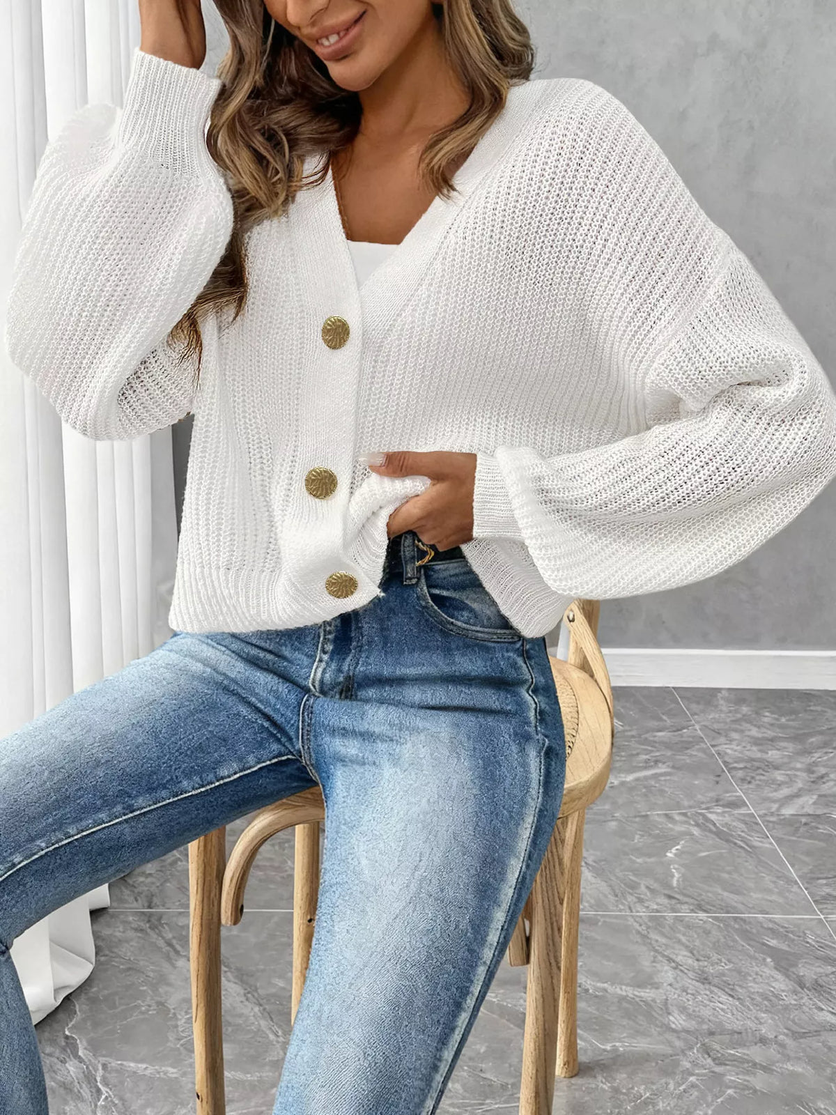 V-neck ribbed knit cardigan in white, buttoned front view seated