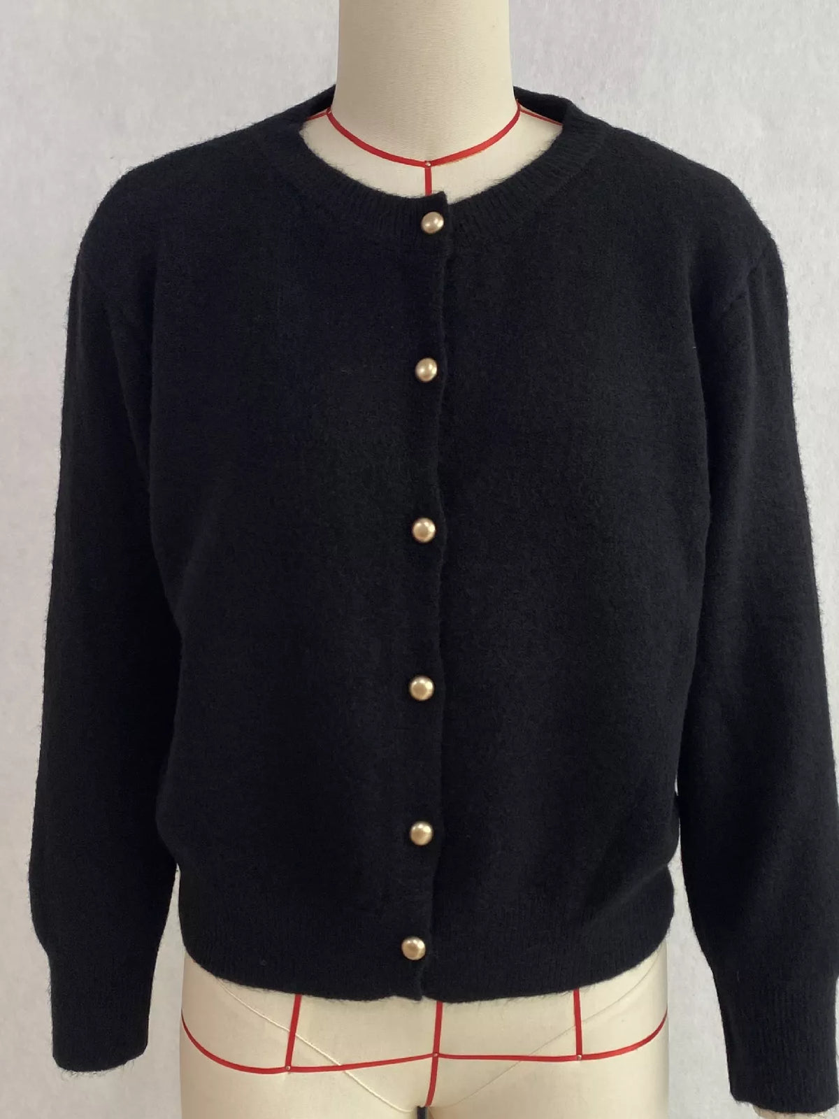 Black round-neck button-front knit cardigan, front on dress form.