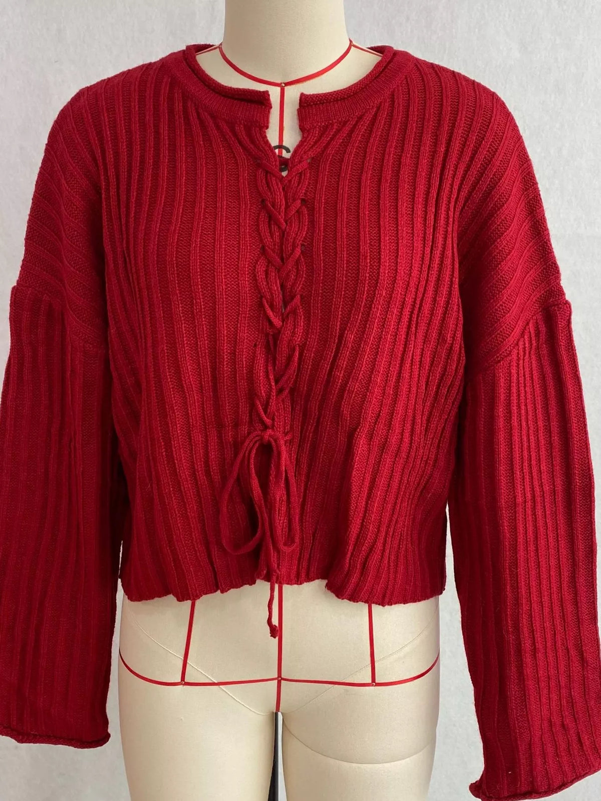 Red ribbed lace-up cropped sweater, front on dress form.