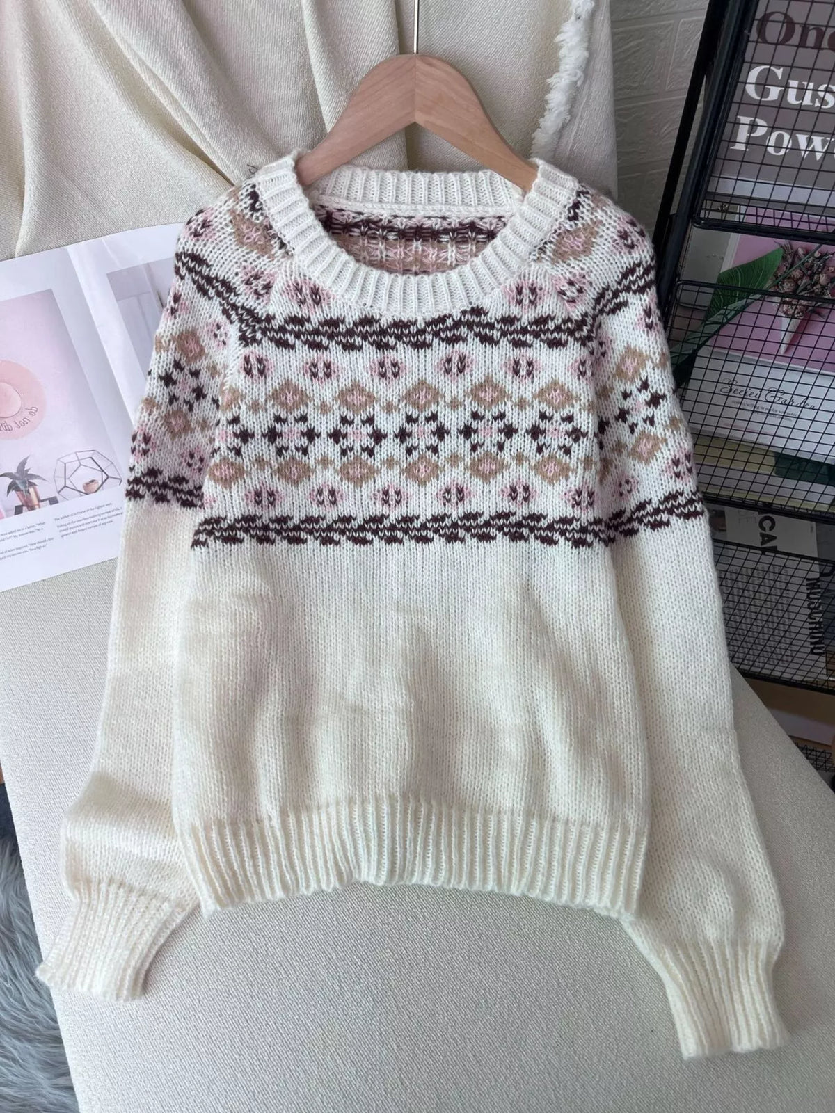 Cream fair isle round-neck sweater, front on hanger.
