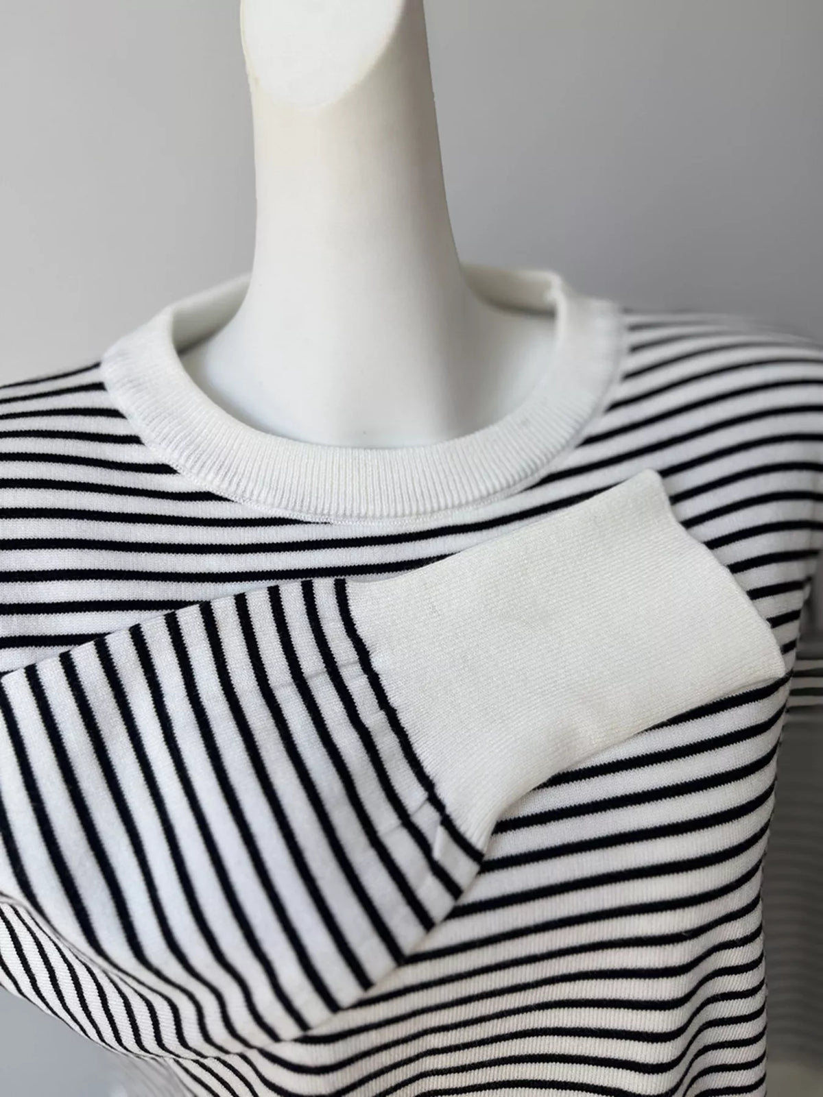 Striped round-neck knit top in white and black, ribbed cuff detail