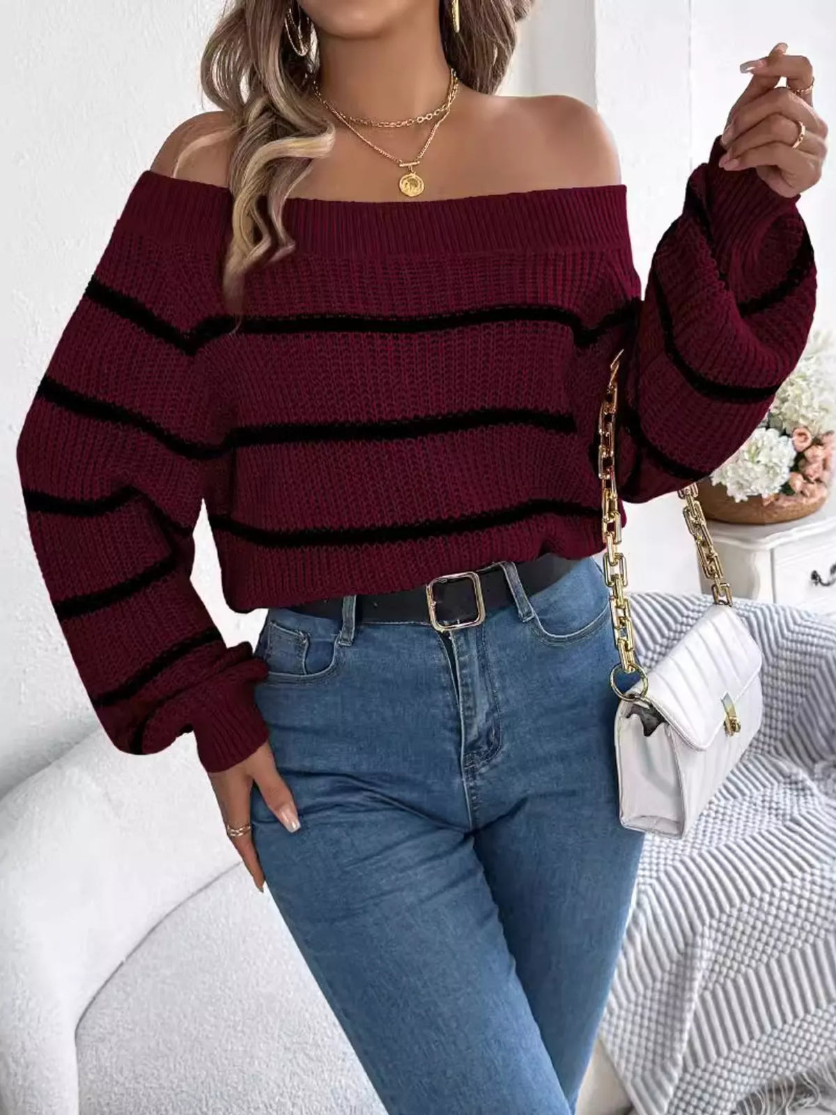 Burgundy off-shoulder striped sweater, front with raised hand.