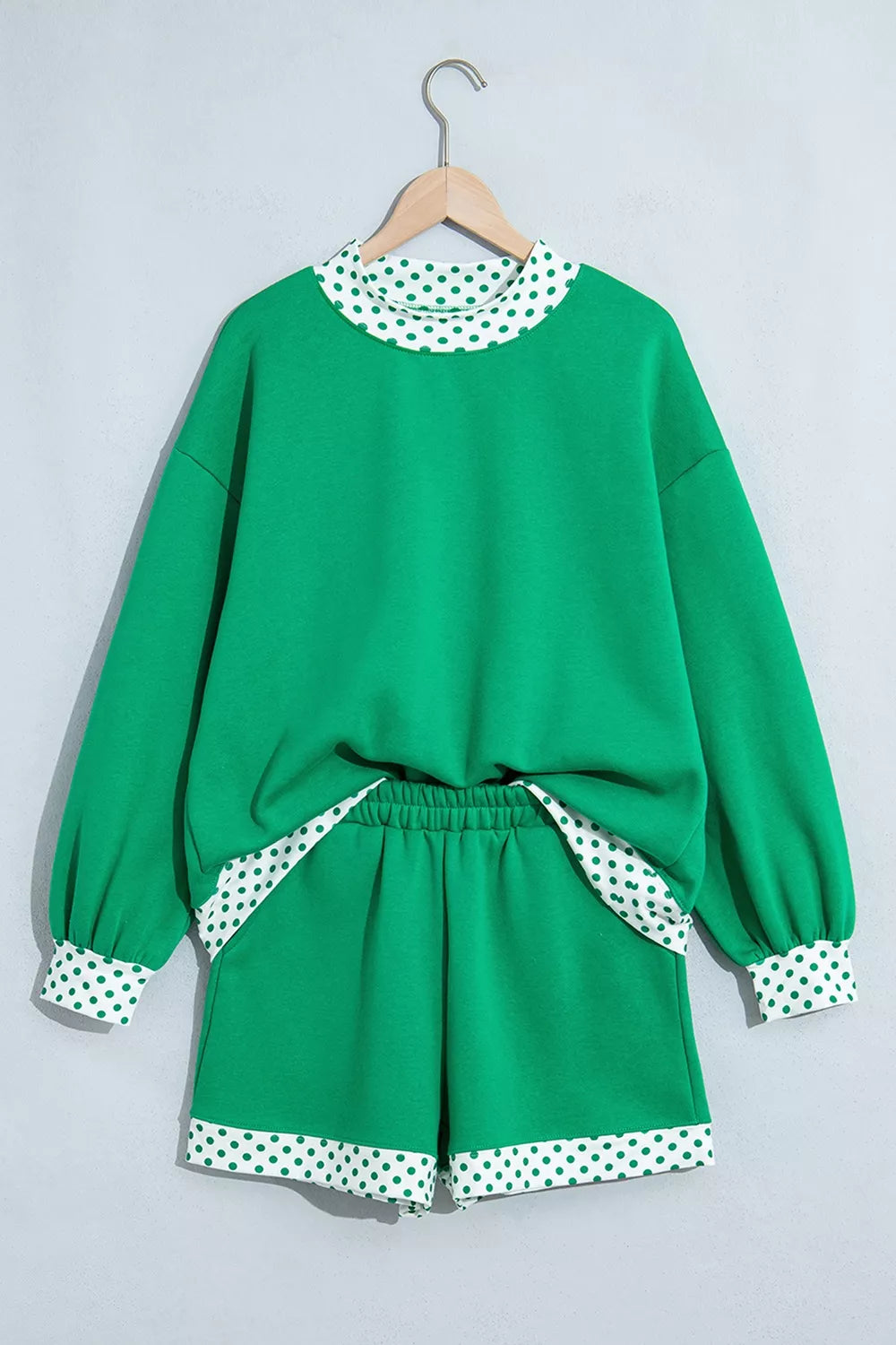 Green sweatshirt and shorts set with polka-dot trim, front on hangers