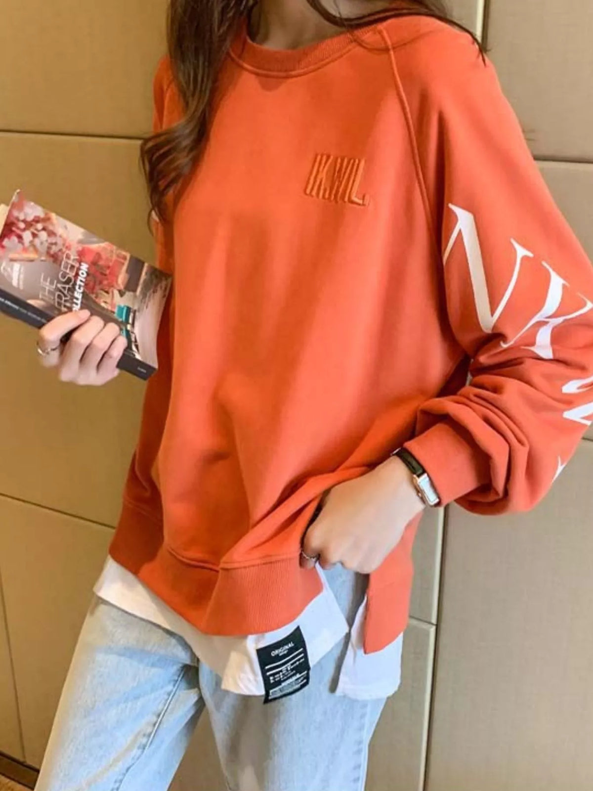 Orange layered-hem sweatshirt with graphic sleeve detail, back view