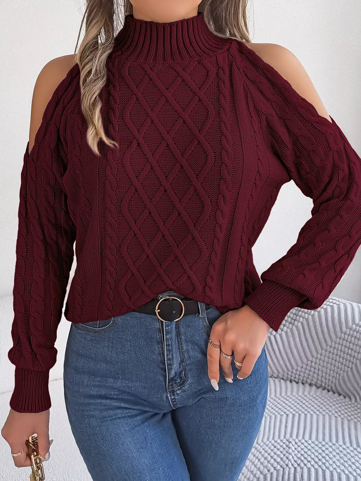 Burgundy cold-shoulder cable-knit sweater, front with hand at waist.
