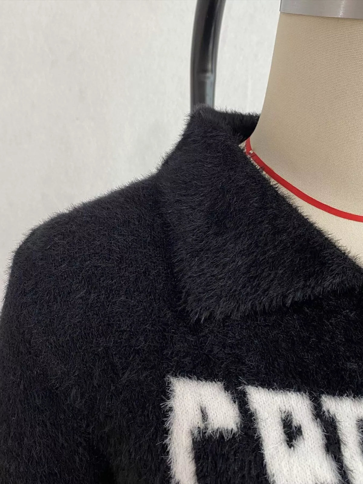 Black fuzzy letter zip-up cardigan, collar and lettering detail.