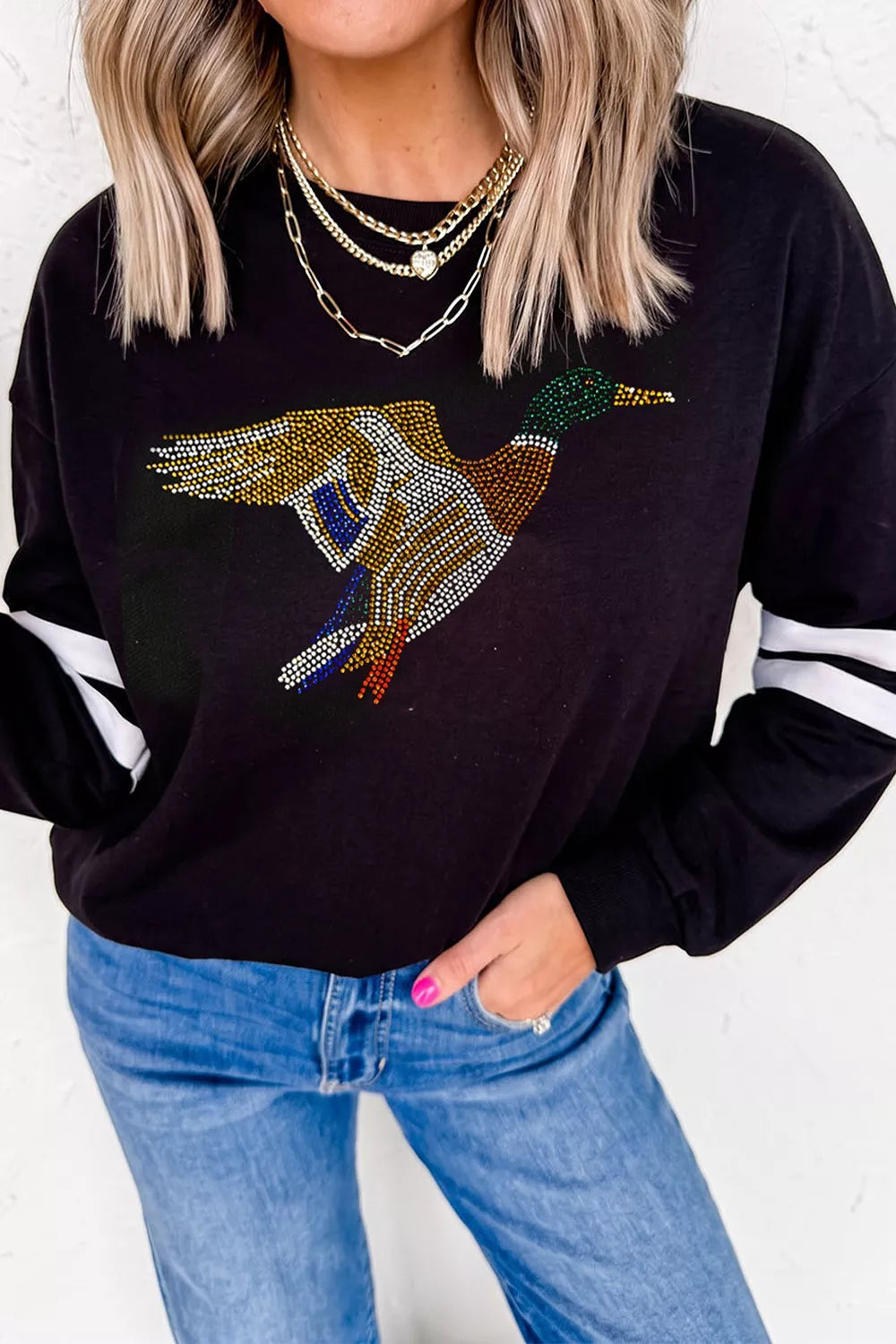 Black rhinestone mallard striped-sleeve sweatshirt, front styled with jeans