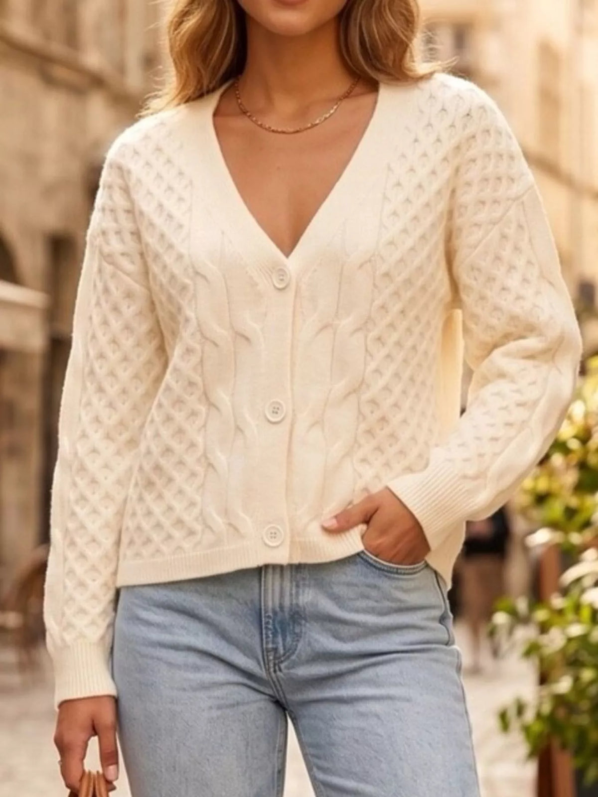 Ivory cable-knit v-neck button-front cardigan, buttoned front view.