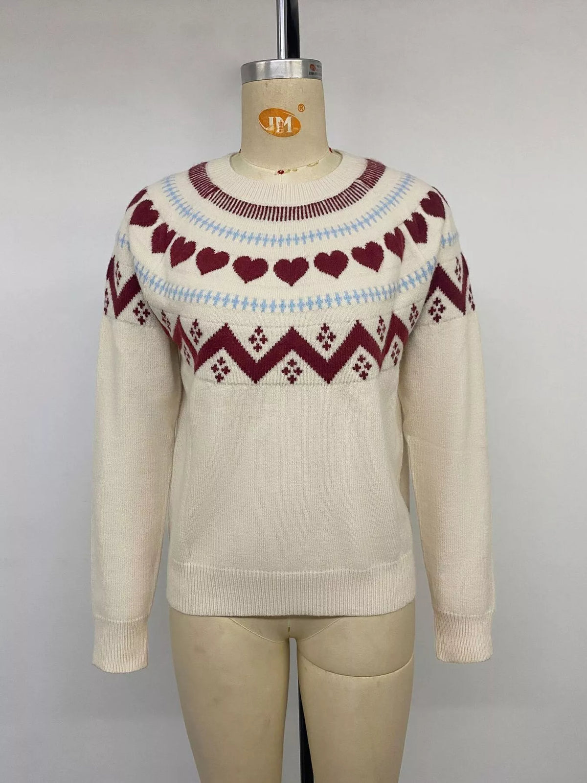Cream heart-patterned crew neck sweater, front on mannequin
