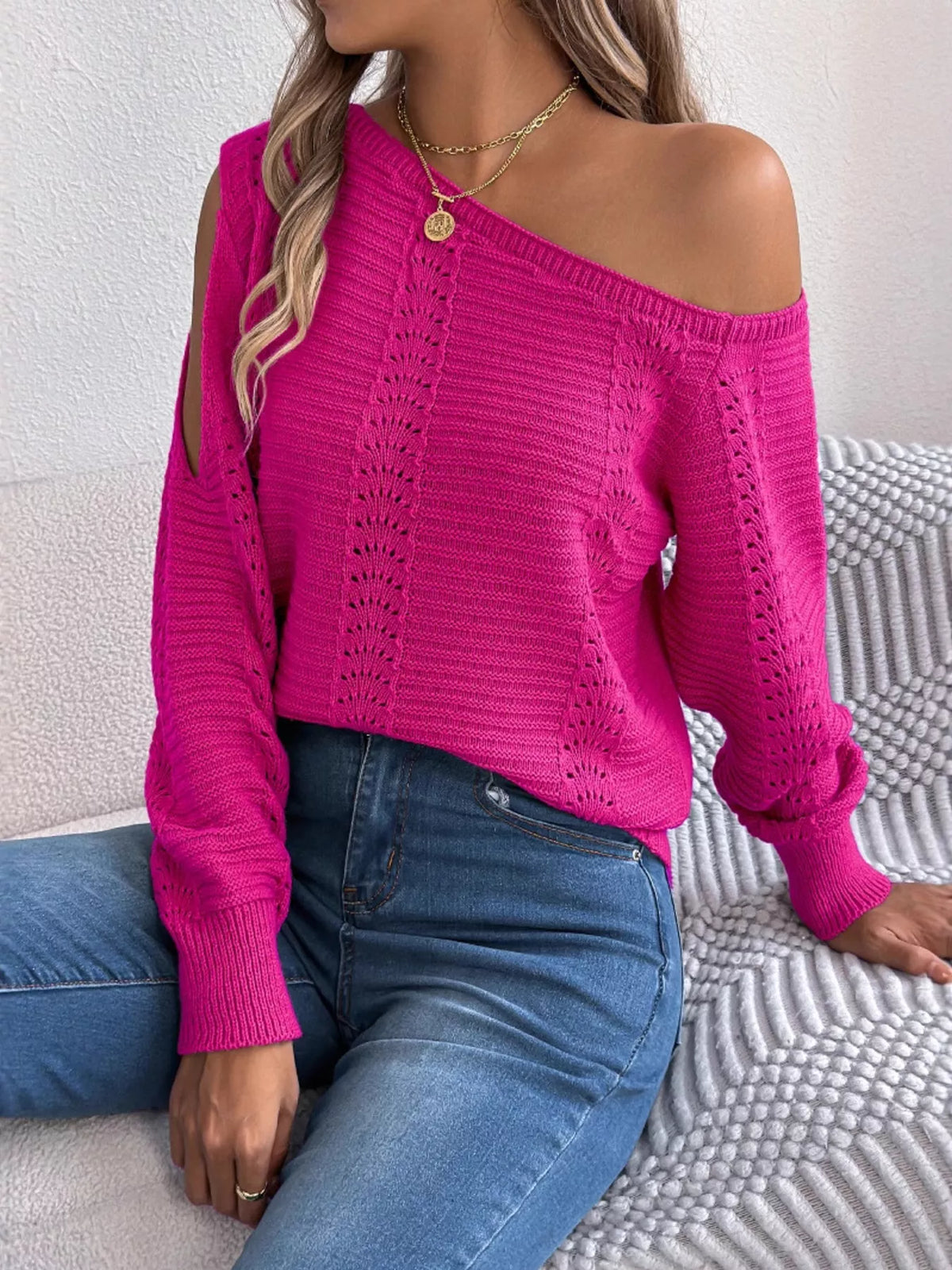 Cerise cold-shoulder openwork knit sweater, seated front view.