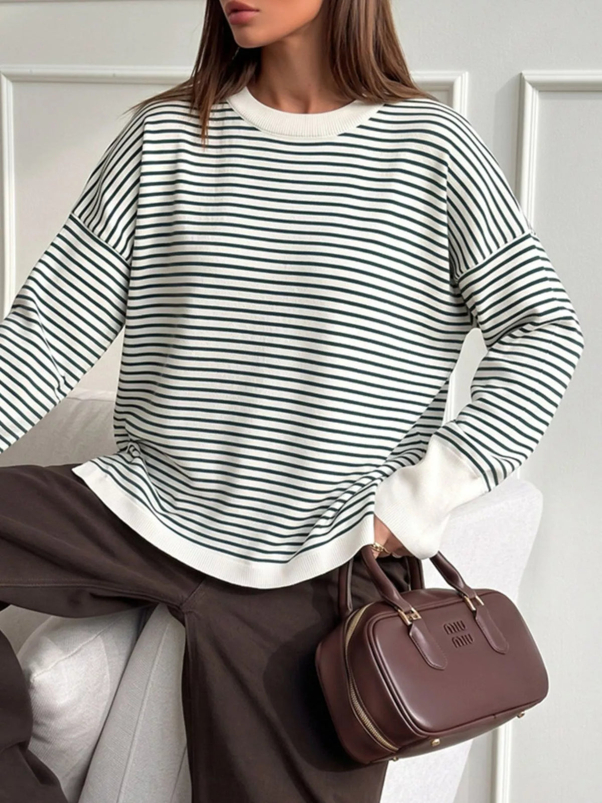 Striped round-neck knit top in white and green, angled seated view