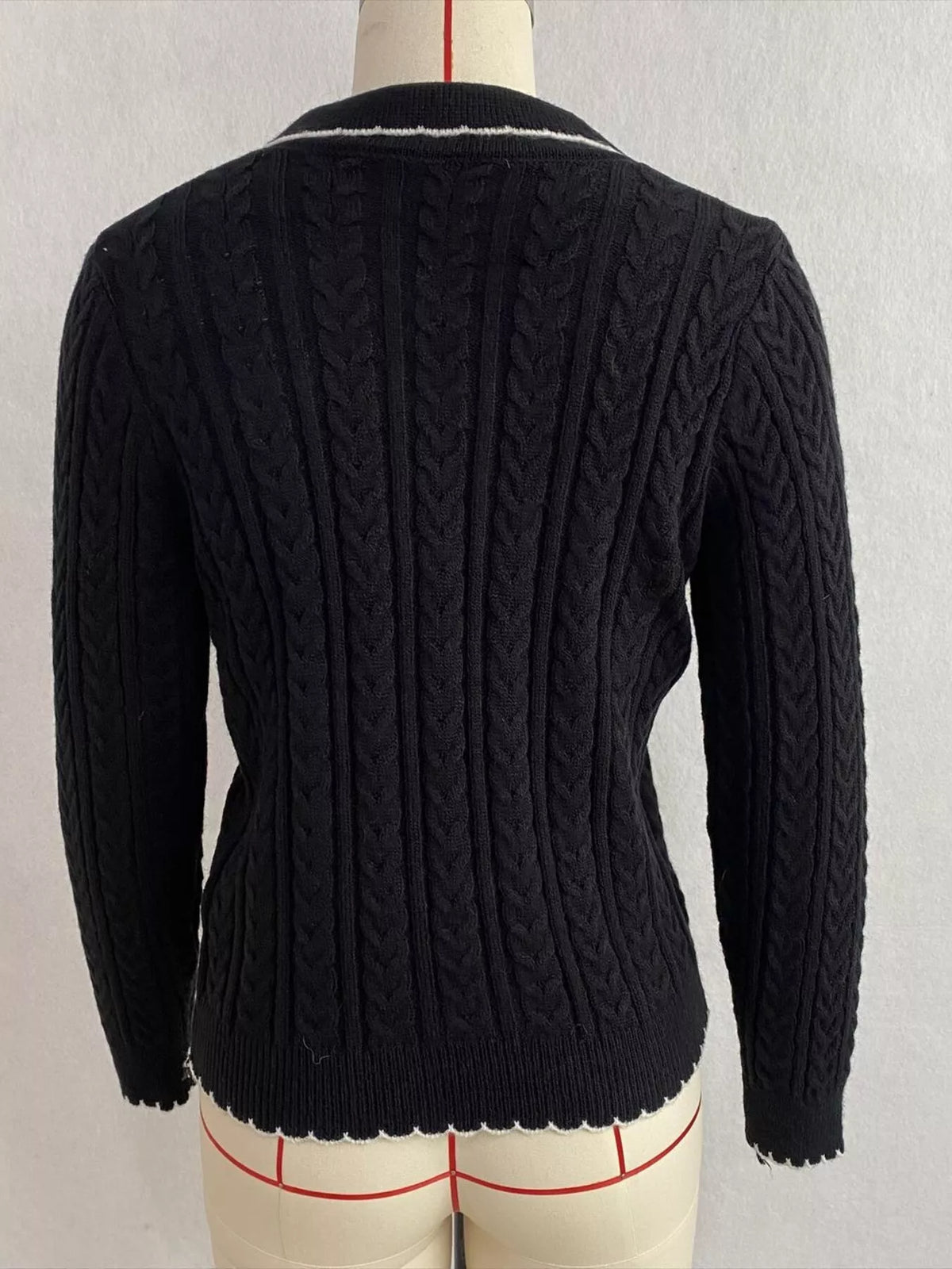 Black cable-knit polo-collar cardigan, back on dress form.