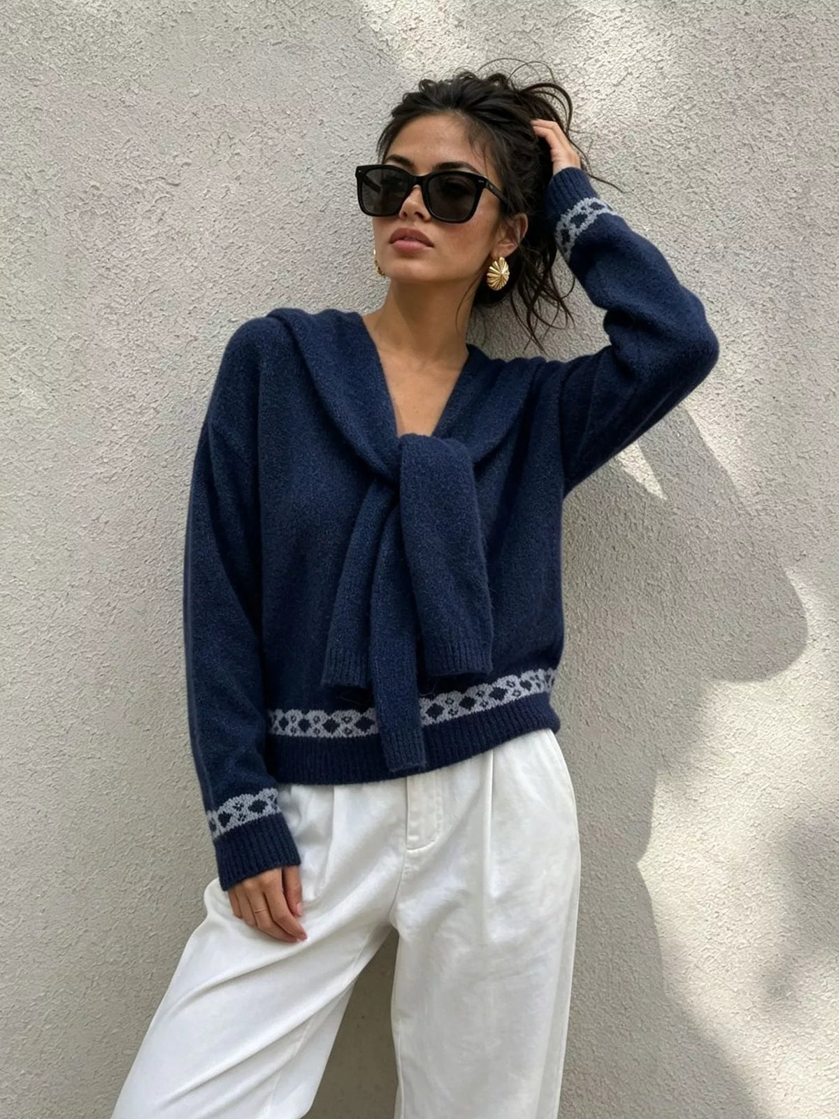 Navy scarf-detail dropped-shoulder sweater, front with raised hand.