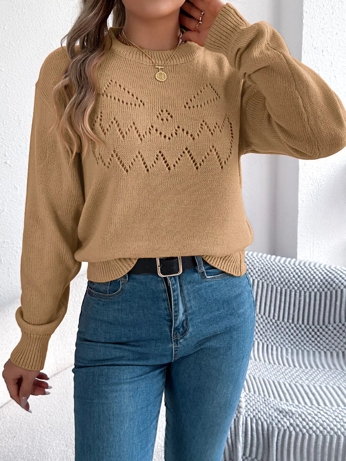 Camel halloween pumpkin face knit sweater, front with raised hand.