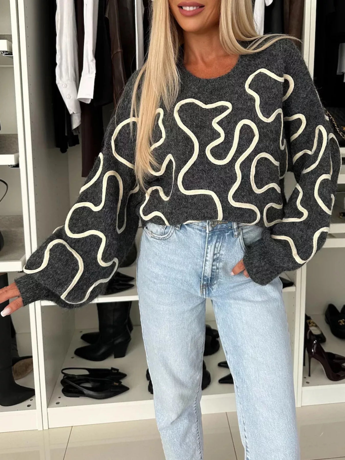 Charcoal abstract pattern oversized crewneck sweater, front with arm extended.