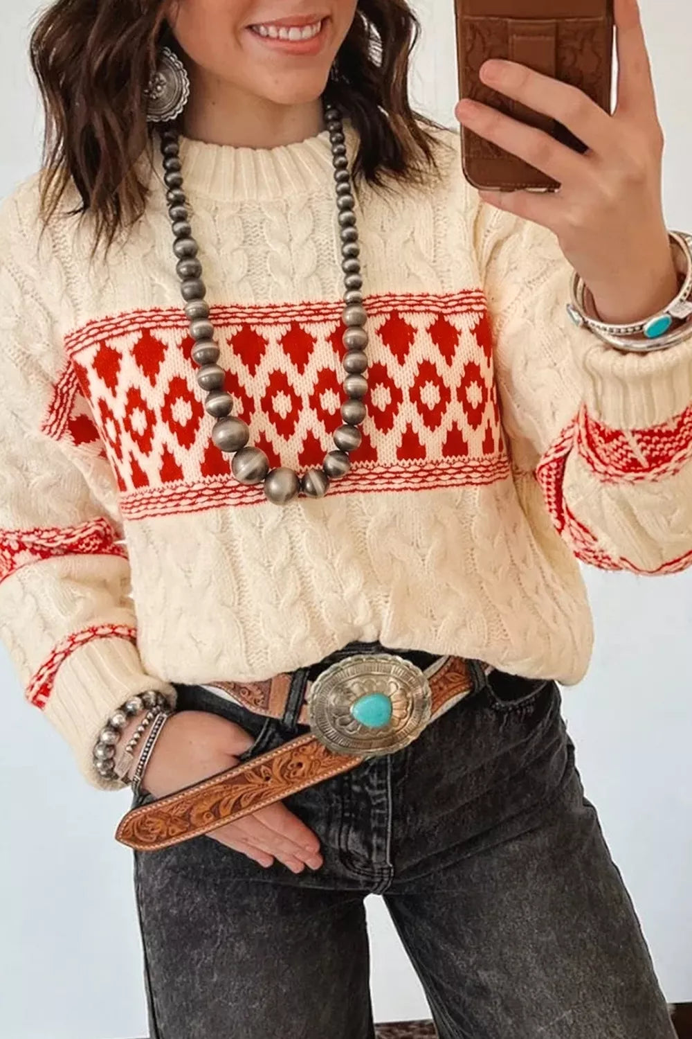 Ivory geometric cable-knit crewneck sweater, front tucked at waist.