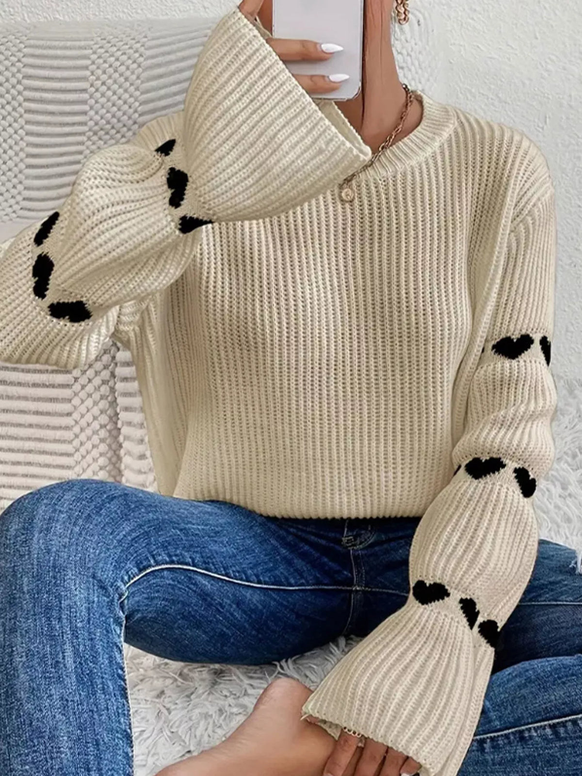 Beige and black heart-sleeve dropped-shoulder sweater, seated front view.