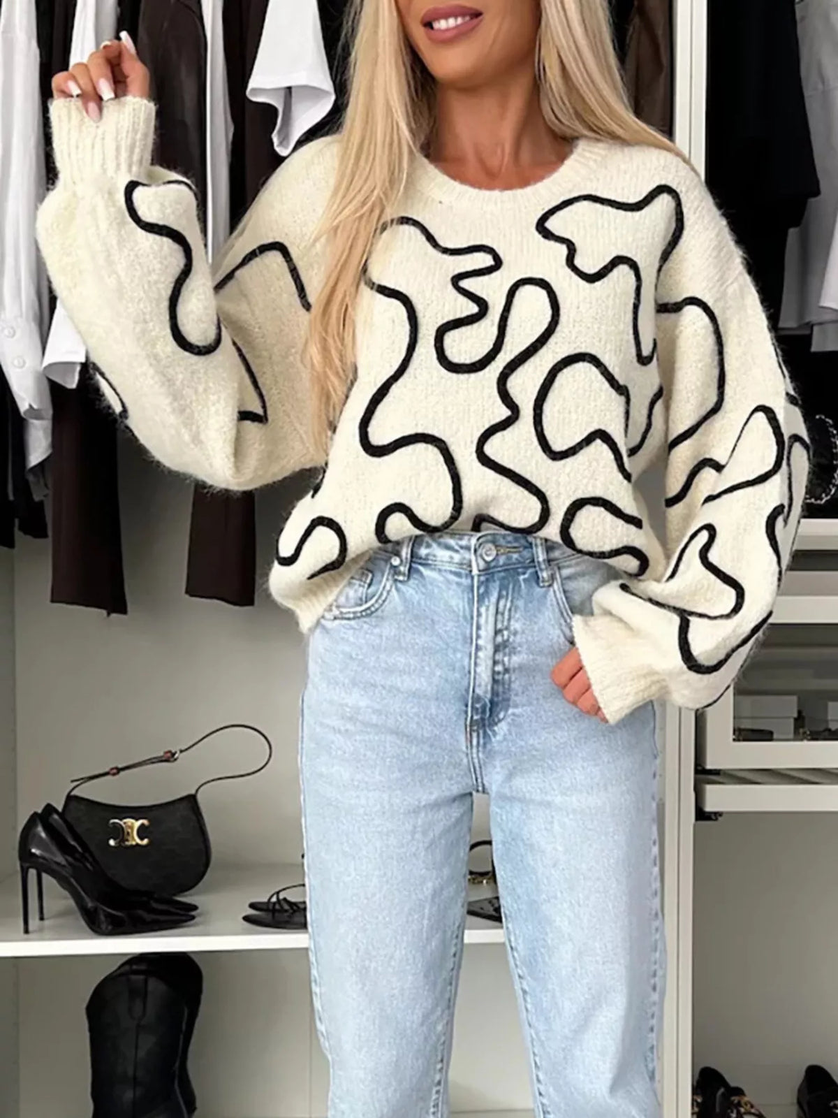 Ivory abstract pattern oversized crewneck sweater, front with raised arm.