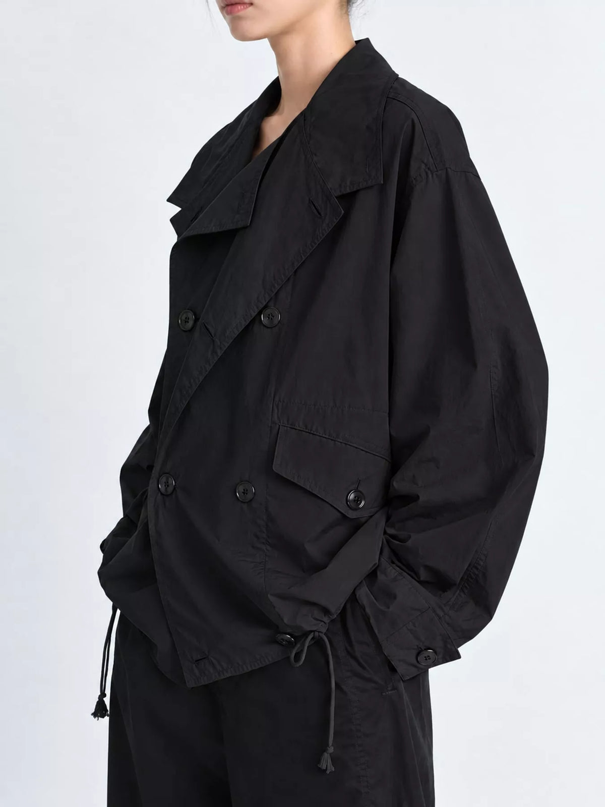 Black double-breasted utility jacket with drawstring hem — side view