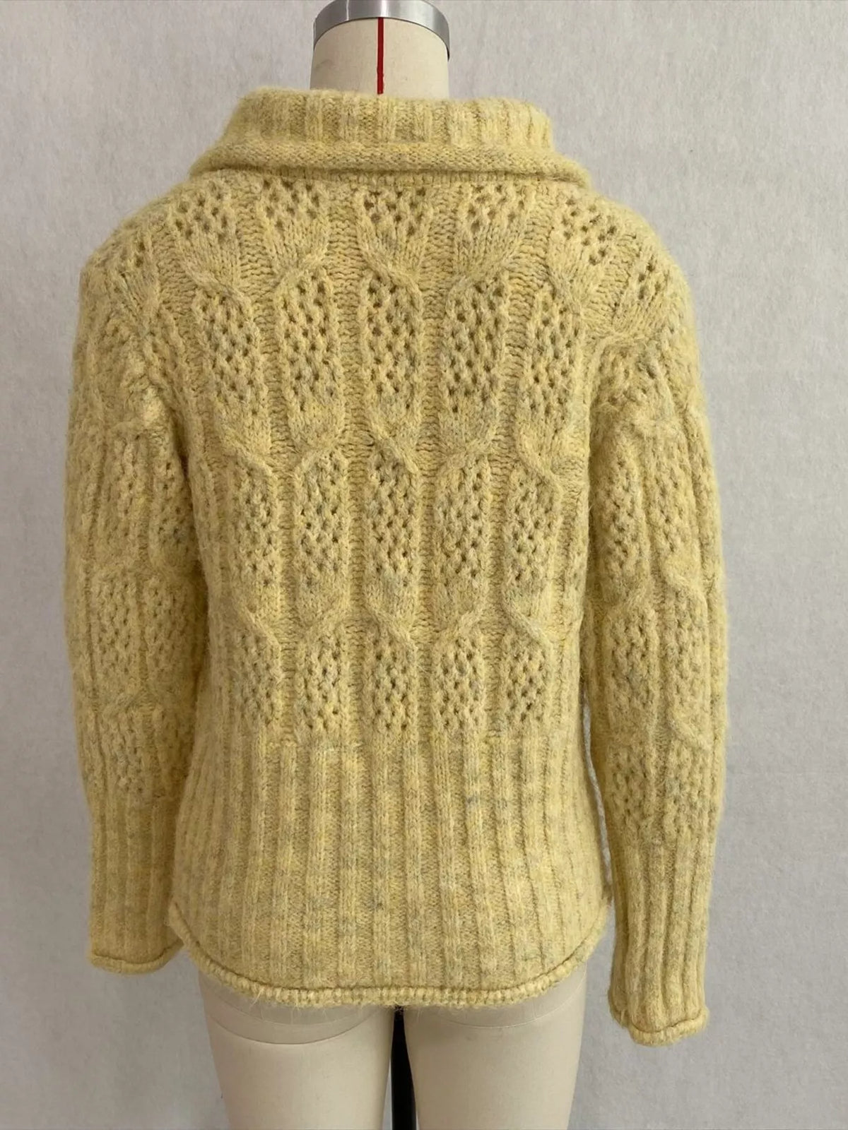 Yellow cable-knit collared button-front cardigan, back on dress form.