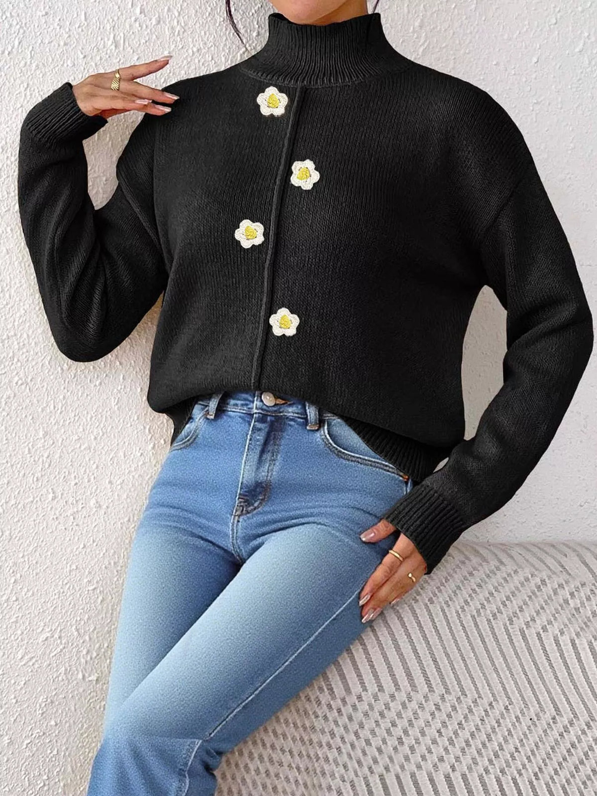 Black floral applique mock-neck sweater, seated front view.