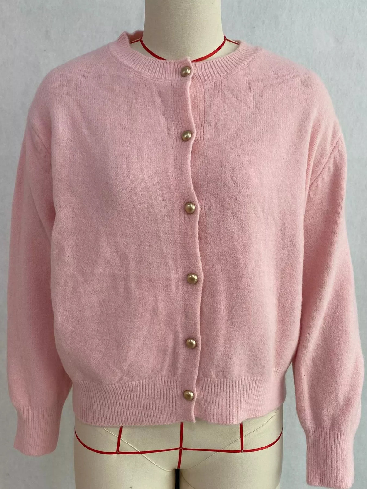 Pink round-neck button-front knit cardigan, front on dress form.