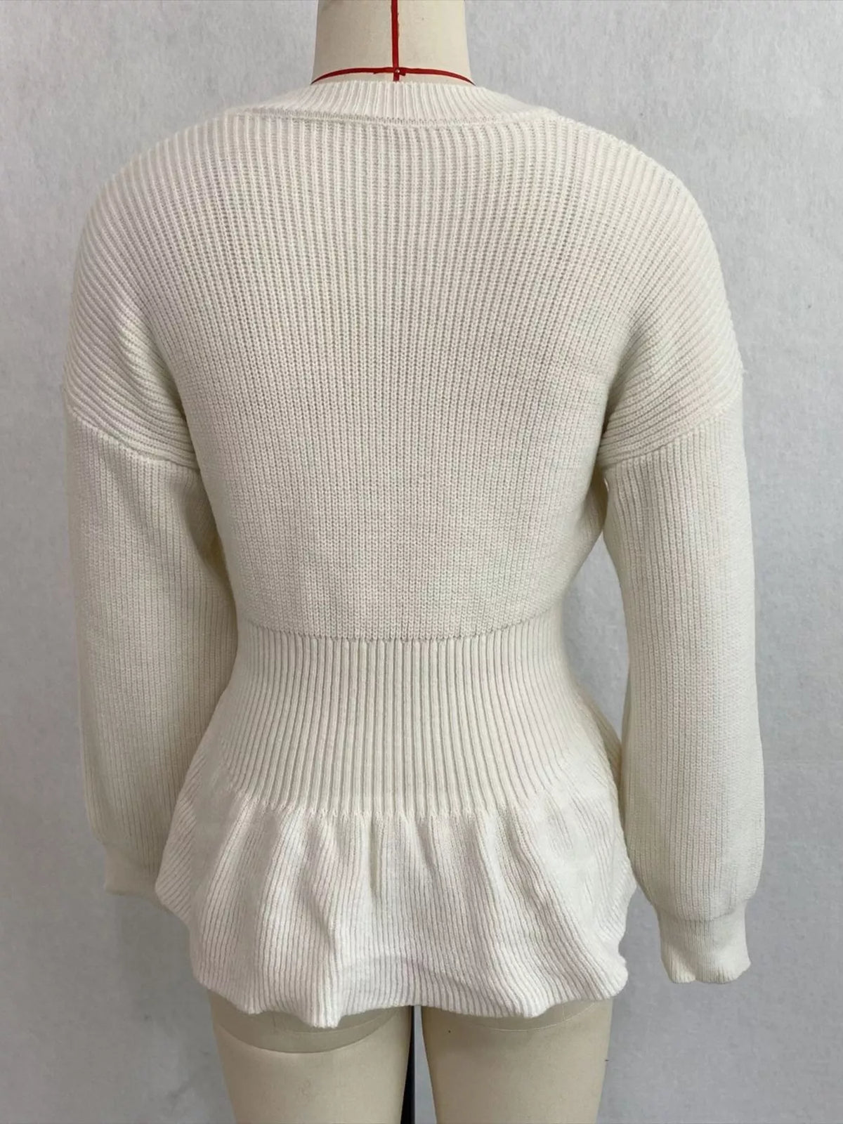 Ivory v-neck peplum-hem knit sweater, back on dress form.