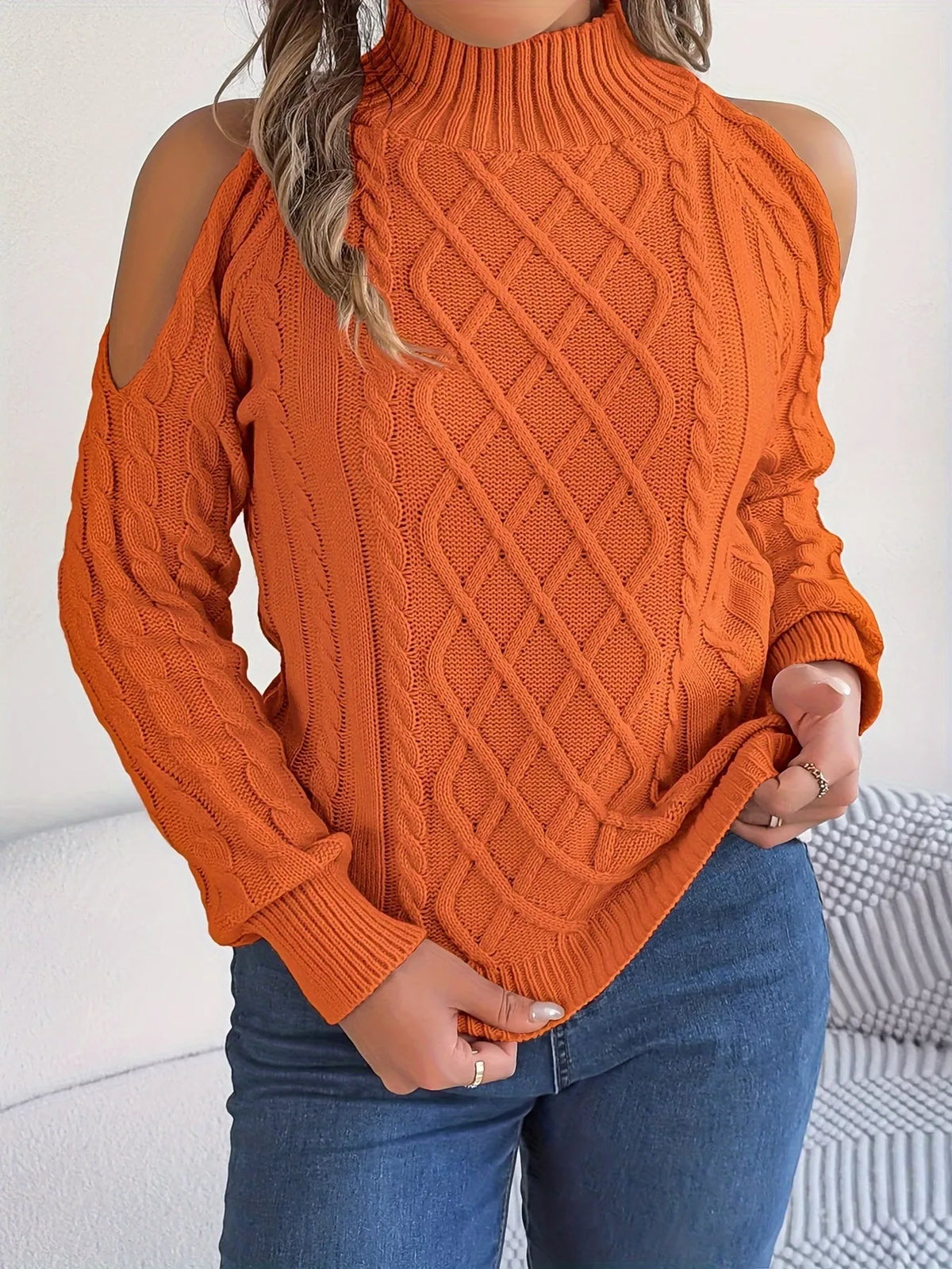 Orange cold-shoulder cable-knit sweater, front holding hem.