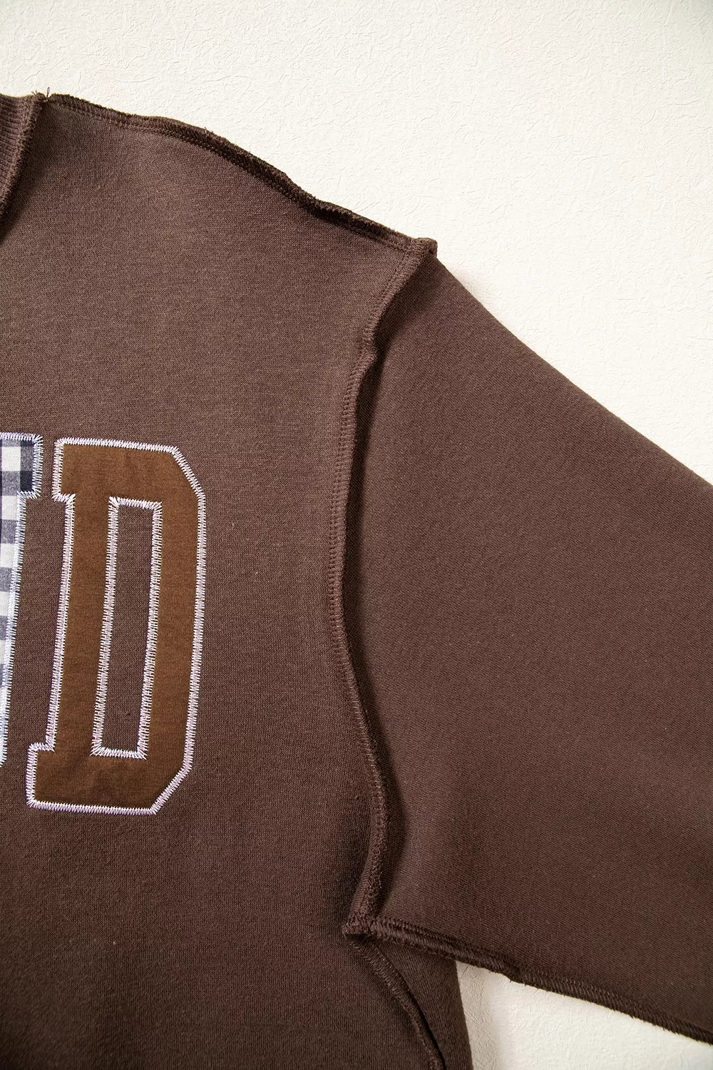 Brown wwjd patchwork graphic mock-neck sweatshirt, shoulder seam detail.