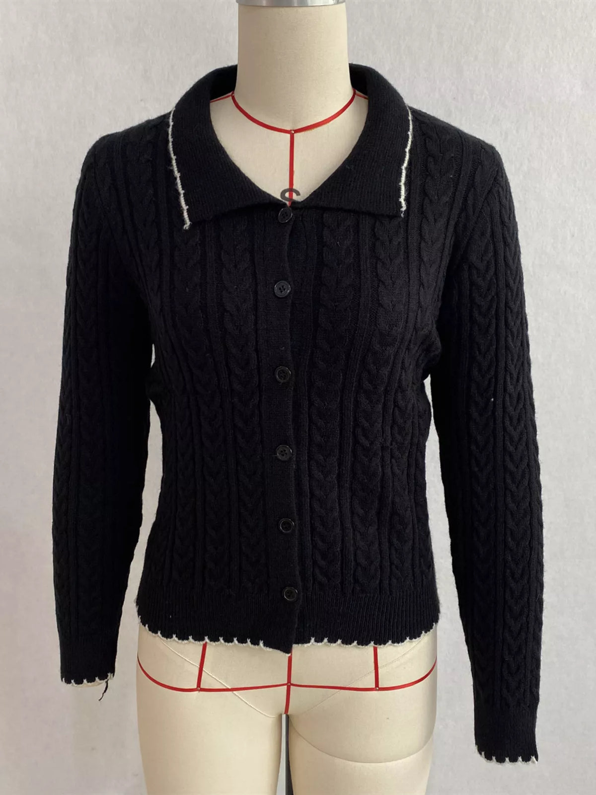 Black cable-knit polo-collar cardigan, front on dress form.