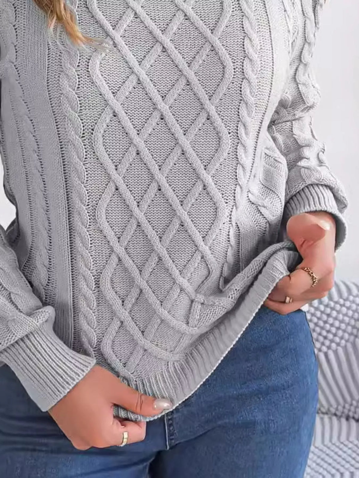 Gray cold-shoulder cable-knit sweater, hem and sleeve detail.