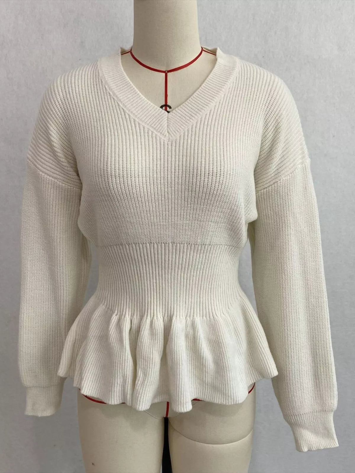 Ivory v-neck peplum-hem knit sweater, front on dress form.