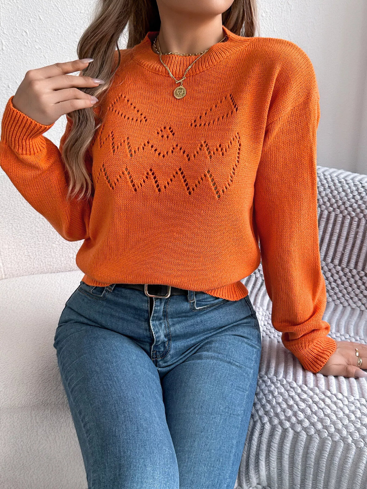 Orange halloween pumpkin face knit sweater, seated front view.