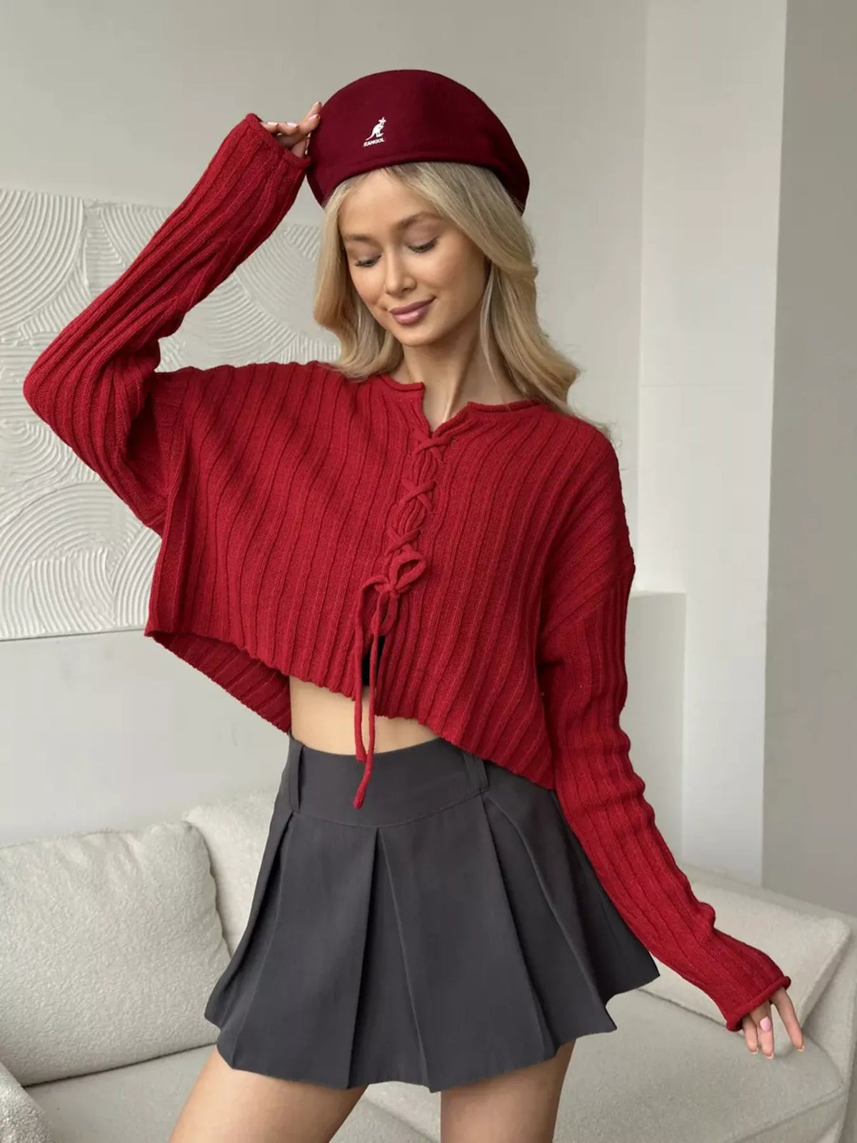 Red ribbed lace-up cropped sweater, front with one arm raised.