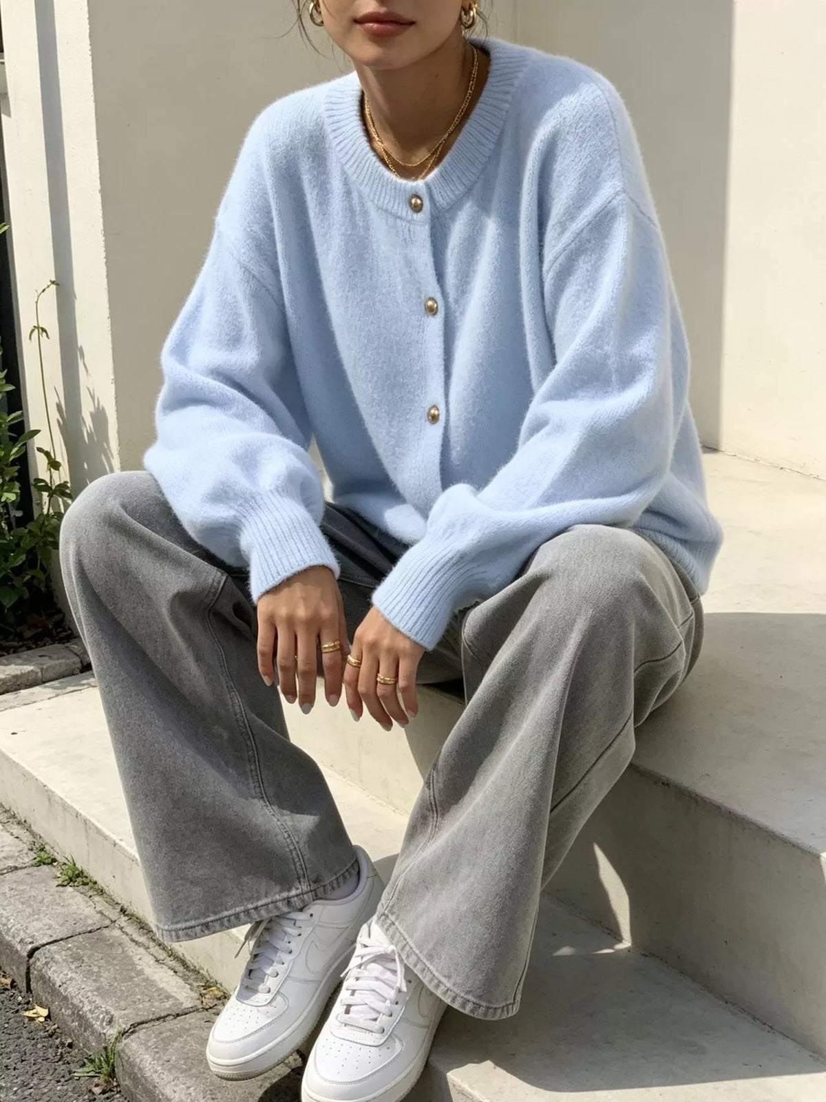Light blue round-neck button-front knit cardigan, seated front view.