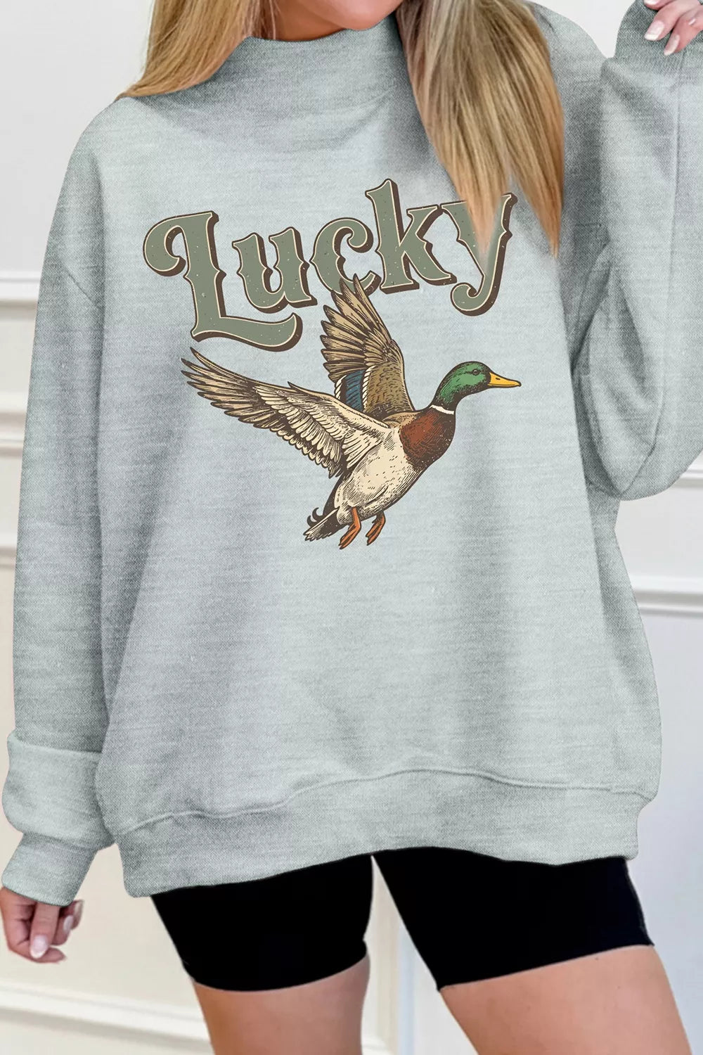 Gray lucky mallard graphic mock-neck sweatshirt, front with one arm raised.