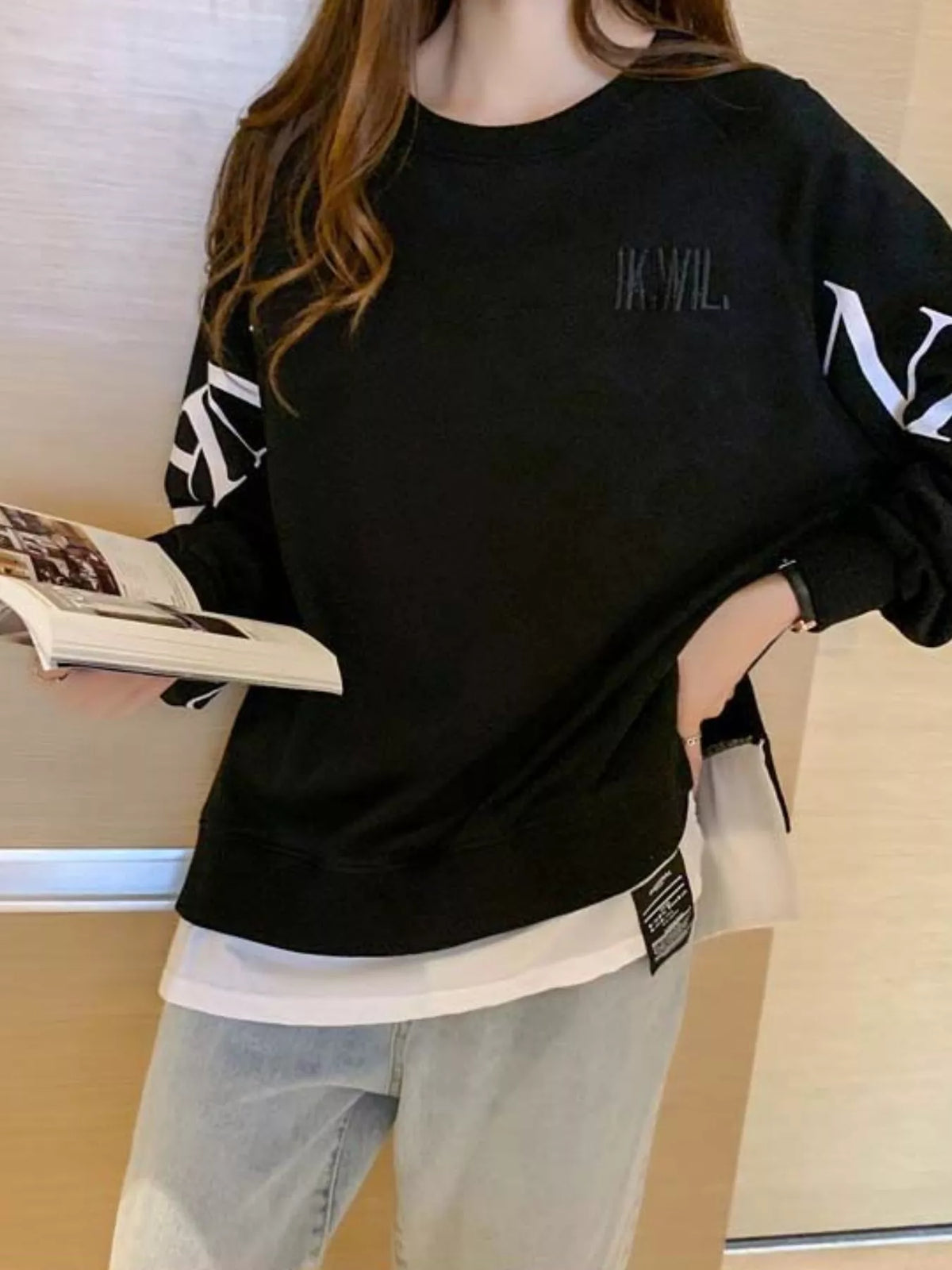 Black layered-hem sweatshirt with graphic sleeve detail, back view