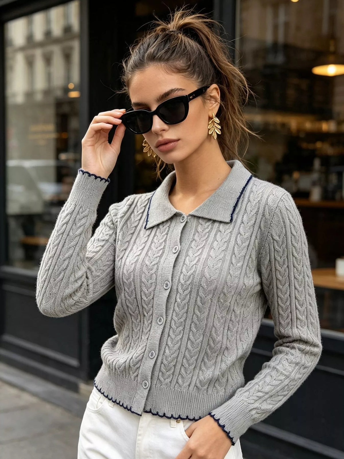 Gray cable-knit polo-collar cardigan, front with raised hand.