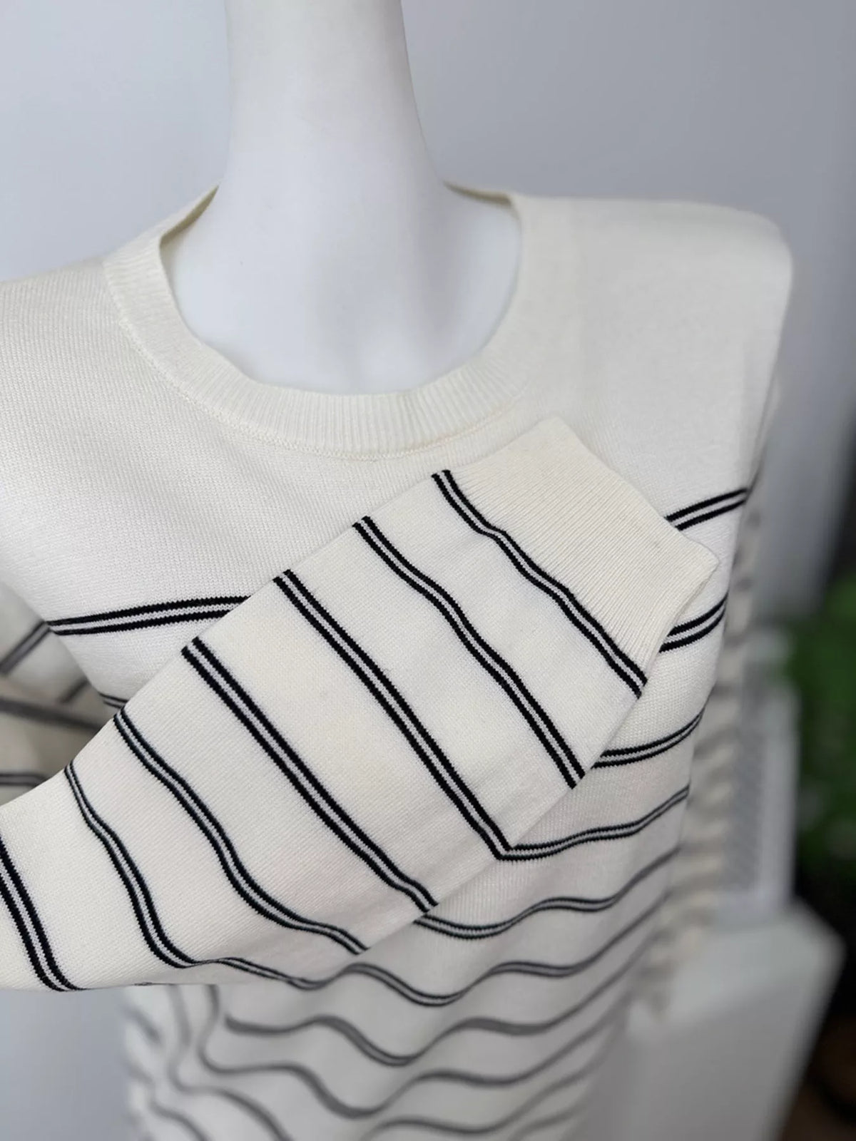 Striped crewneck sweater with layered tie detail in white and black, cuff detail