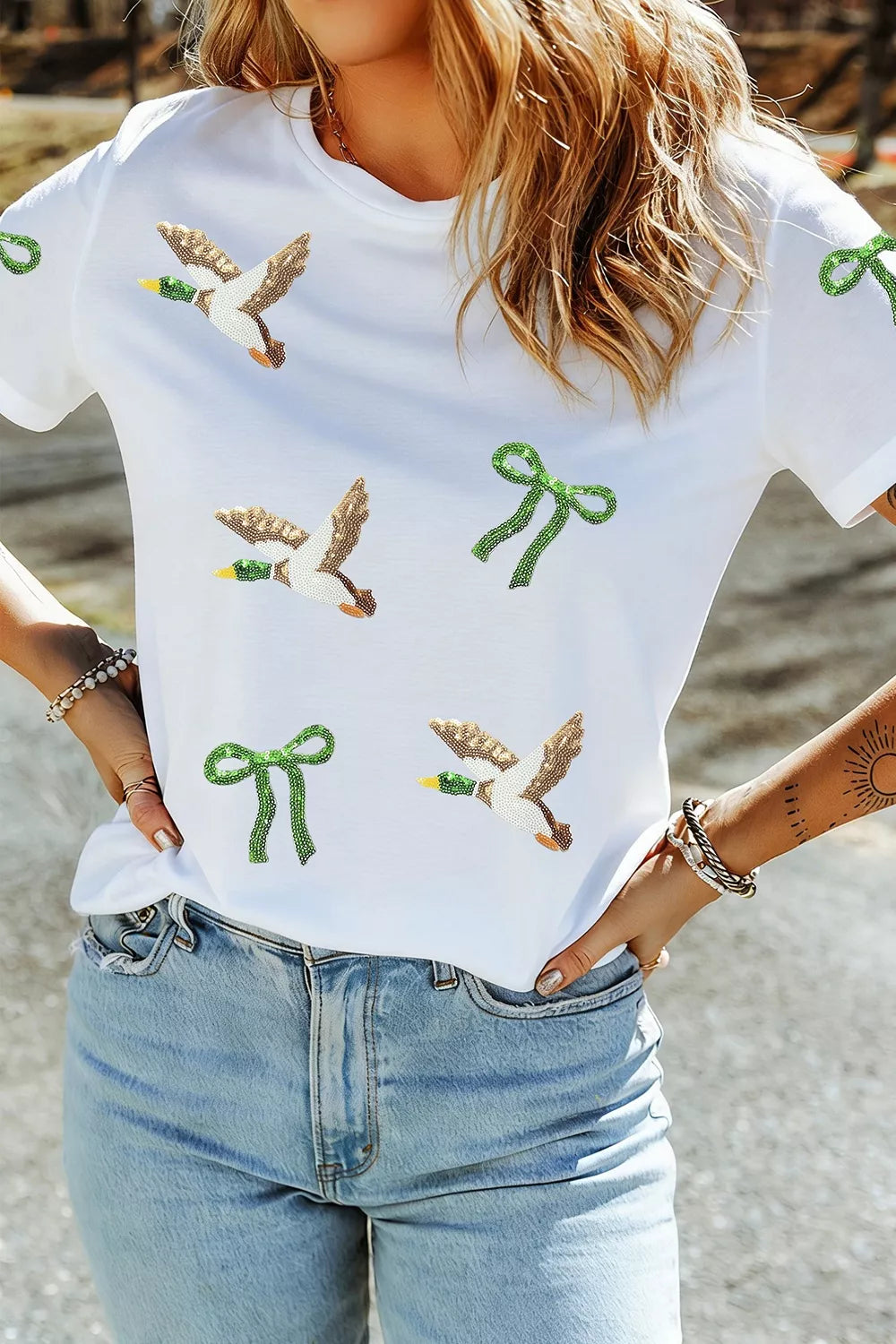 White sequin mallard and bow graphic t-shirt, front view tucked into jeans.