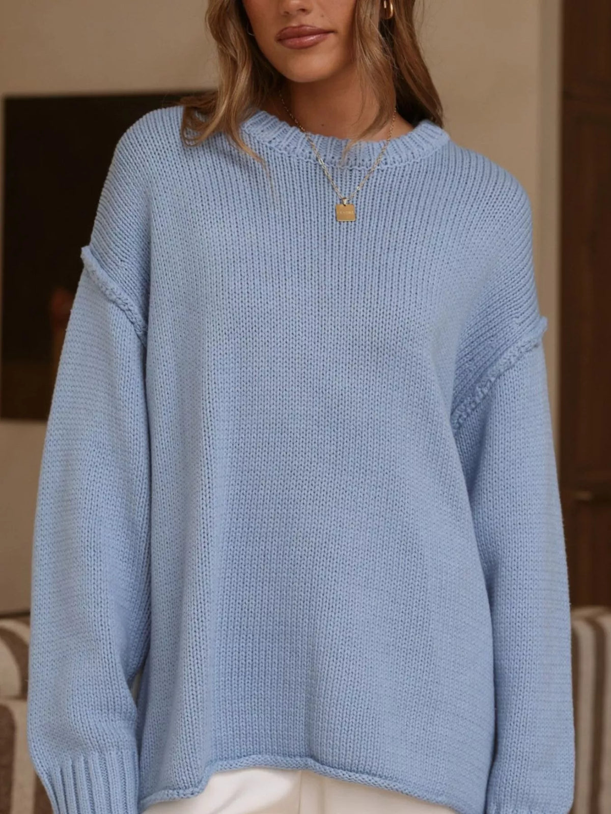 Light blue crewneck dropped-shoulder sweater, front knit detail.